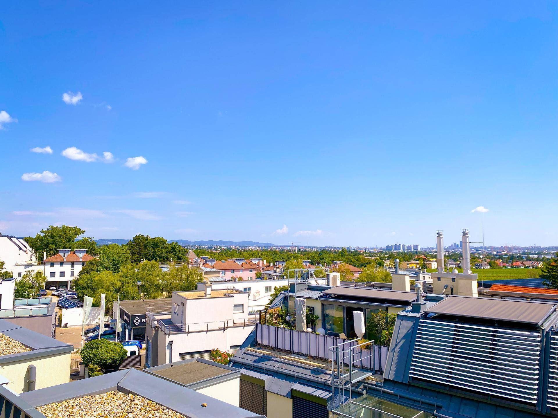 Weitläufiger Panoramablick über die Stadt und grüne Umgebung von der Dachterrasse.