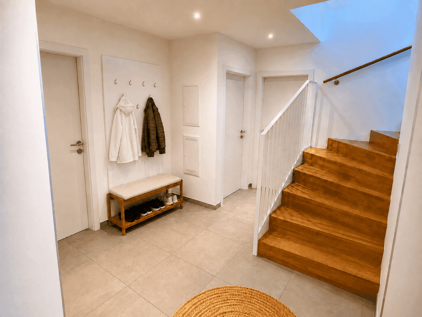 Geräumiger Eingangsbereich mit Garderobe, Holztreppe und Fliesenboden.