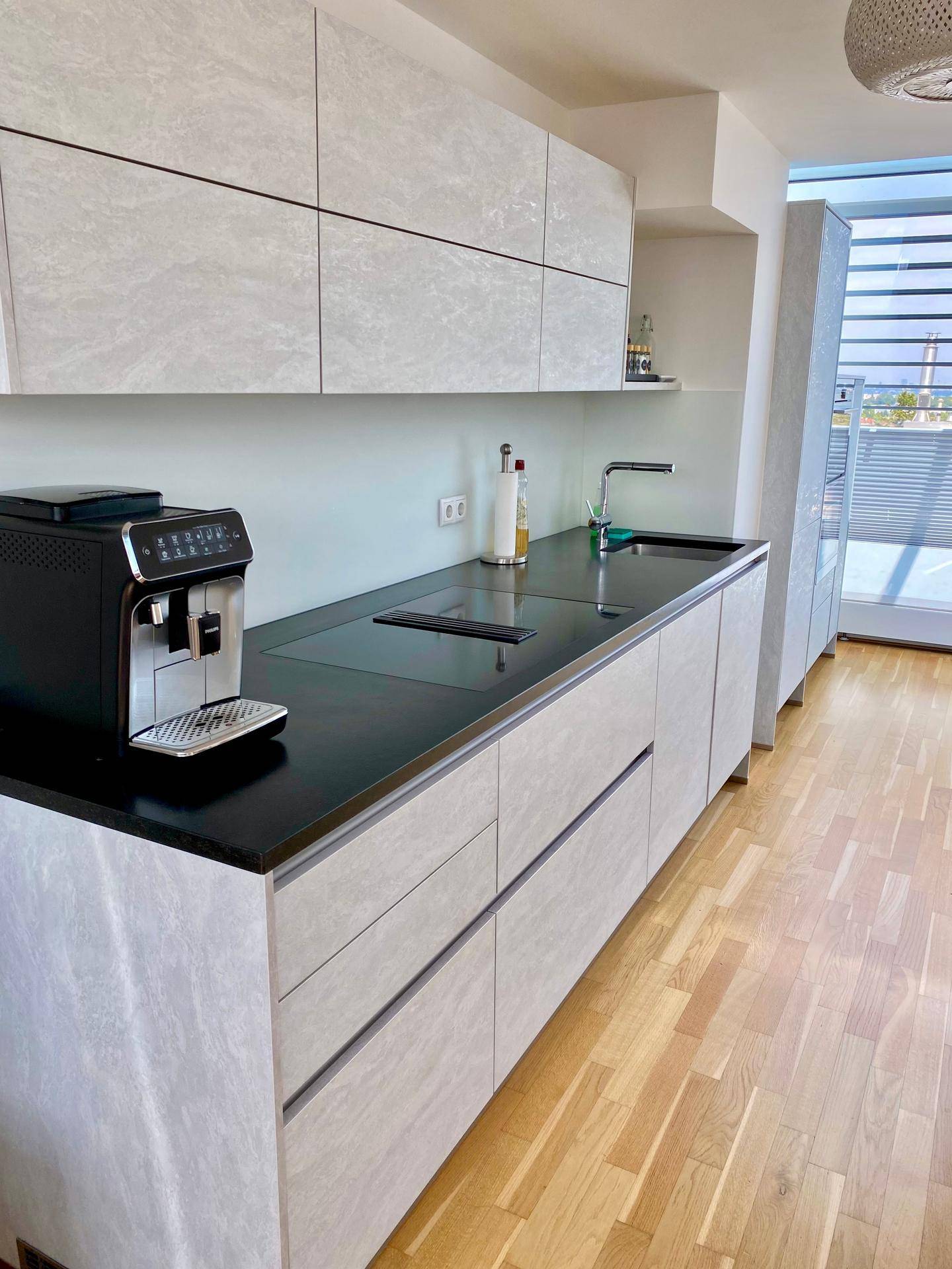 Moderne Küchenzeile mit integriertem Kochfeld, Spüle und Kaffeemaschine.