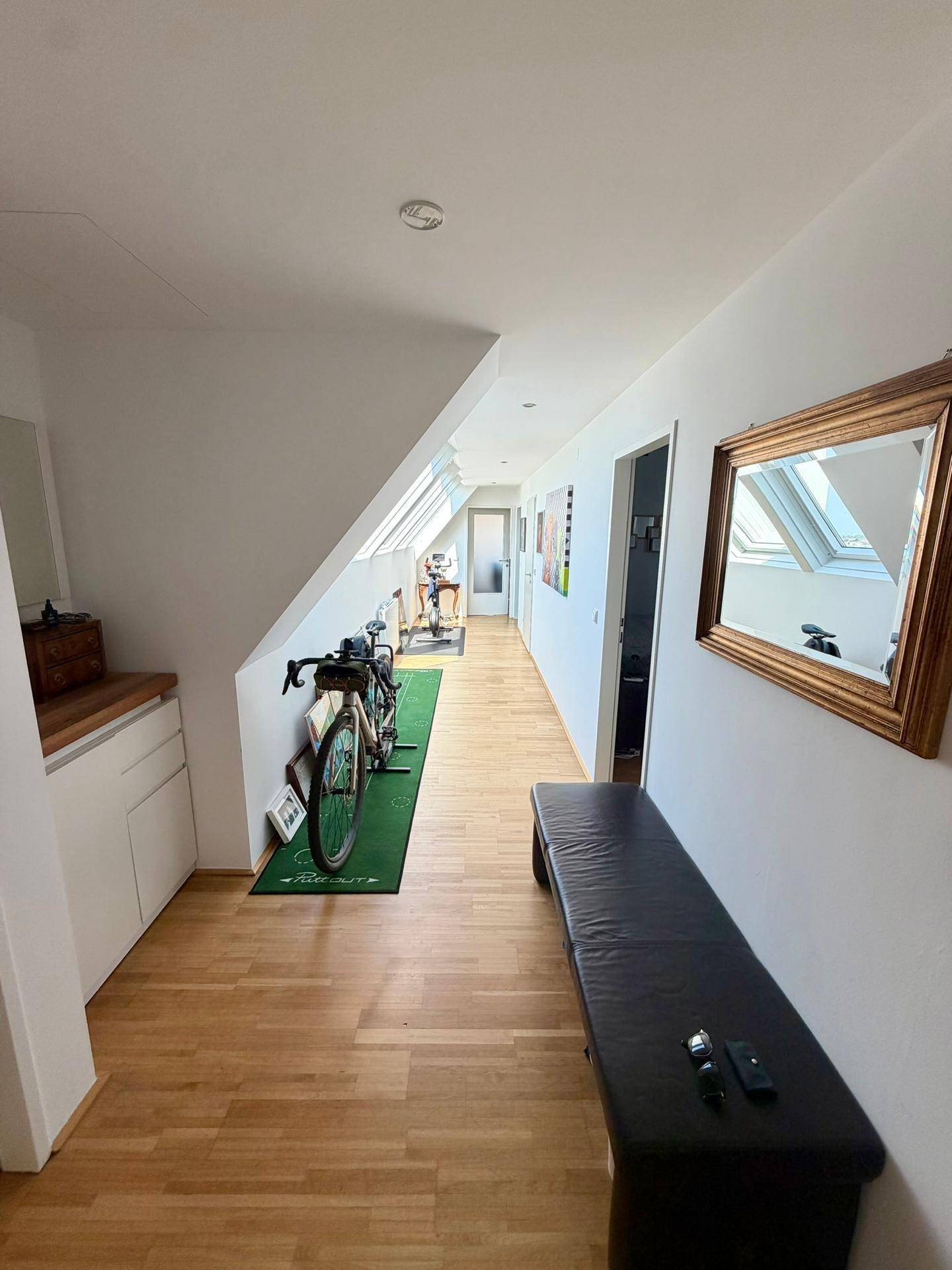 Geräumiger Flur mit Holzparkettboden, Dachschrägen und einem Spiegel an der Wand.