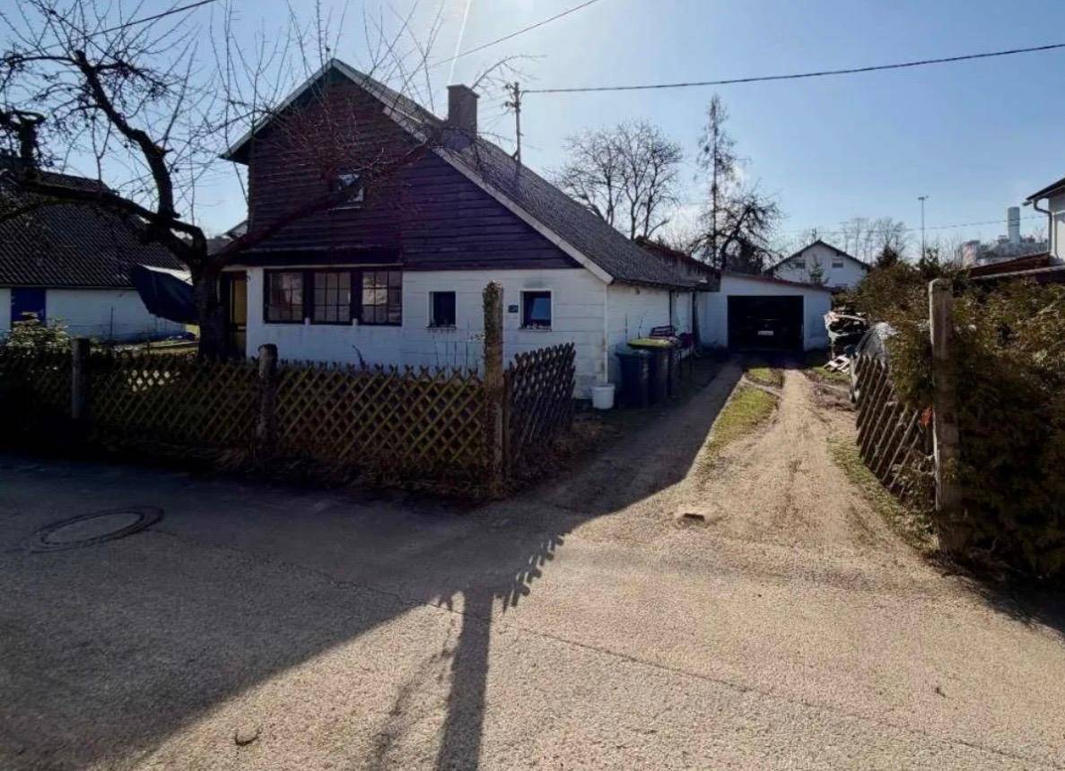 Seitenansicht des Hauses mit langer Schotterauffahrt, die zu einer Garage oder einem Nebengebäude führt.