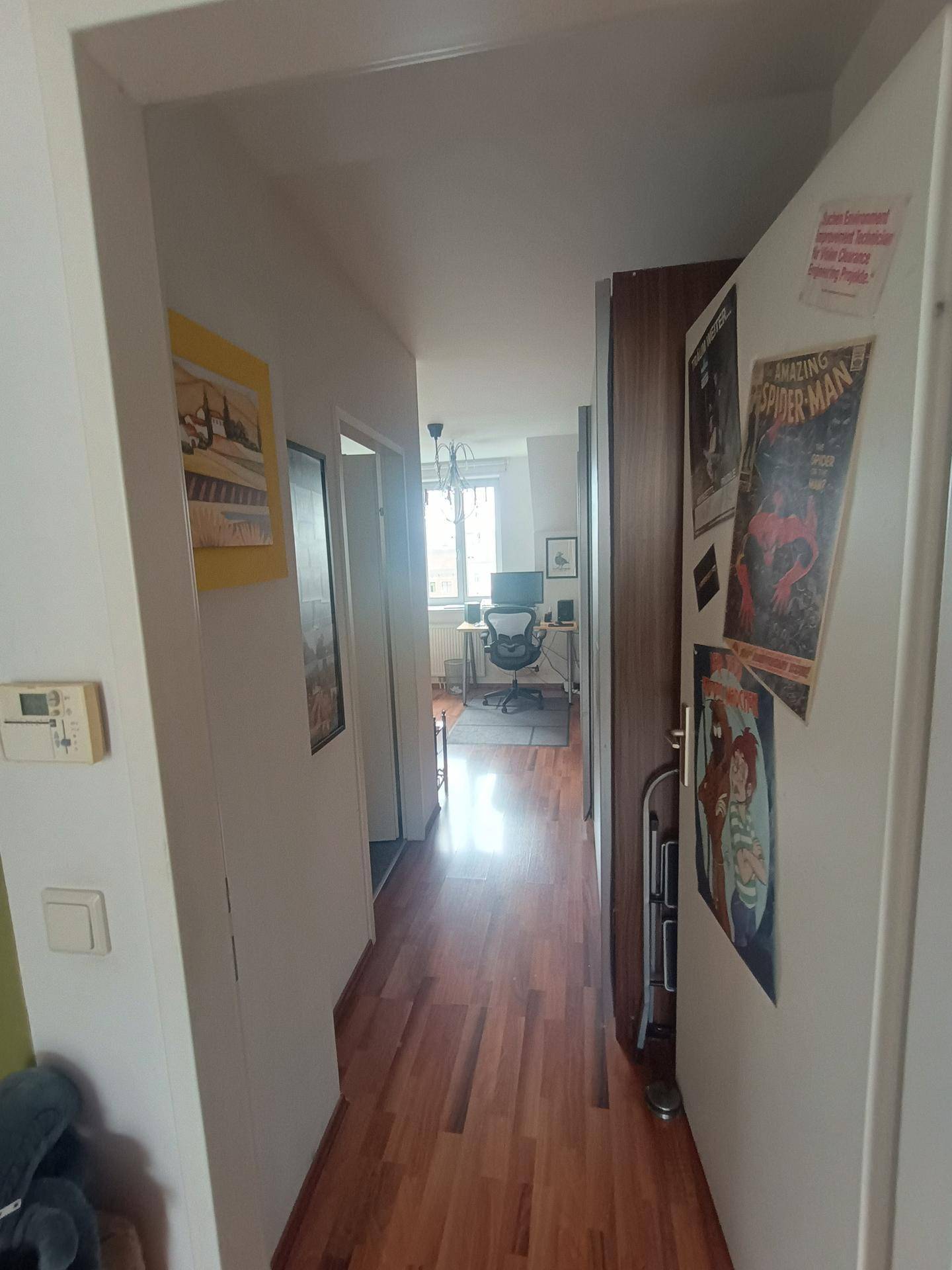 Langer Flur mit Holzboden, der zu einem weiteren Zimmer mit Fenster führt.