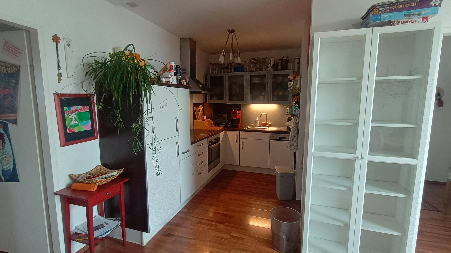 Funktionale Küche mit weißen Schränken, Holzboden und integrierten Geräten.