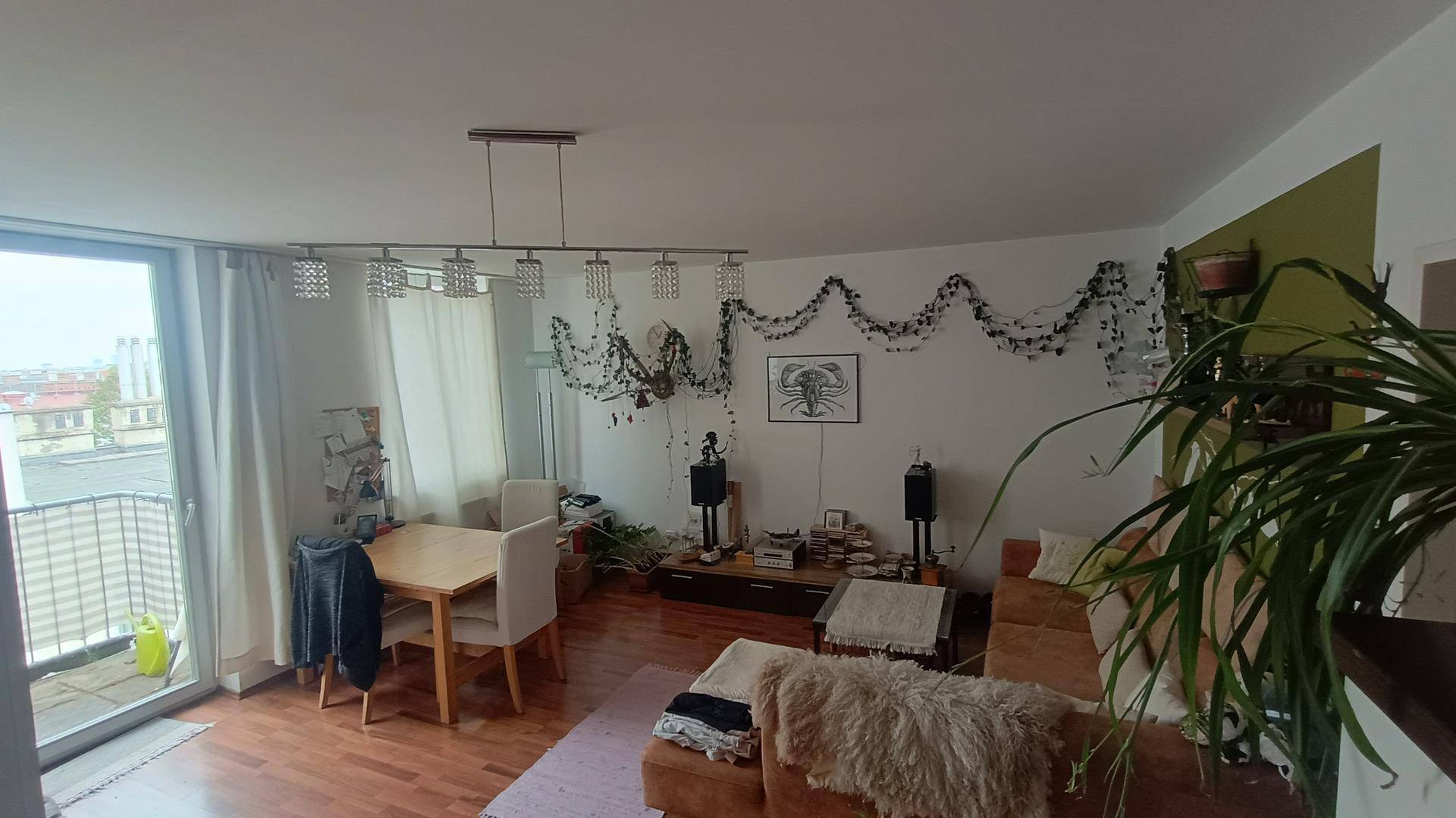 Heller Wohn-Essbereich mit Holzboden, Zugang zum Balkon und gemütlicher Einrichtung.