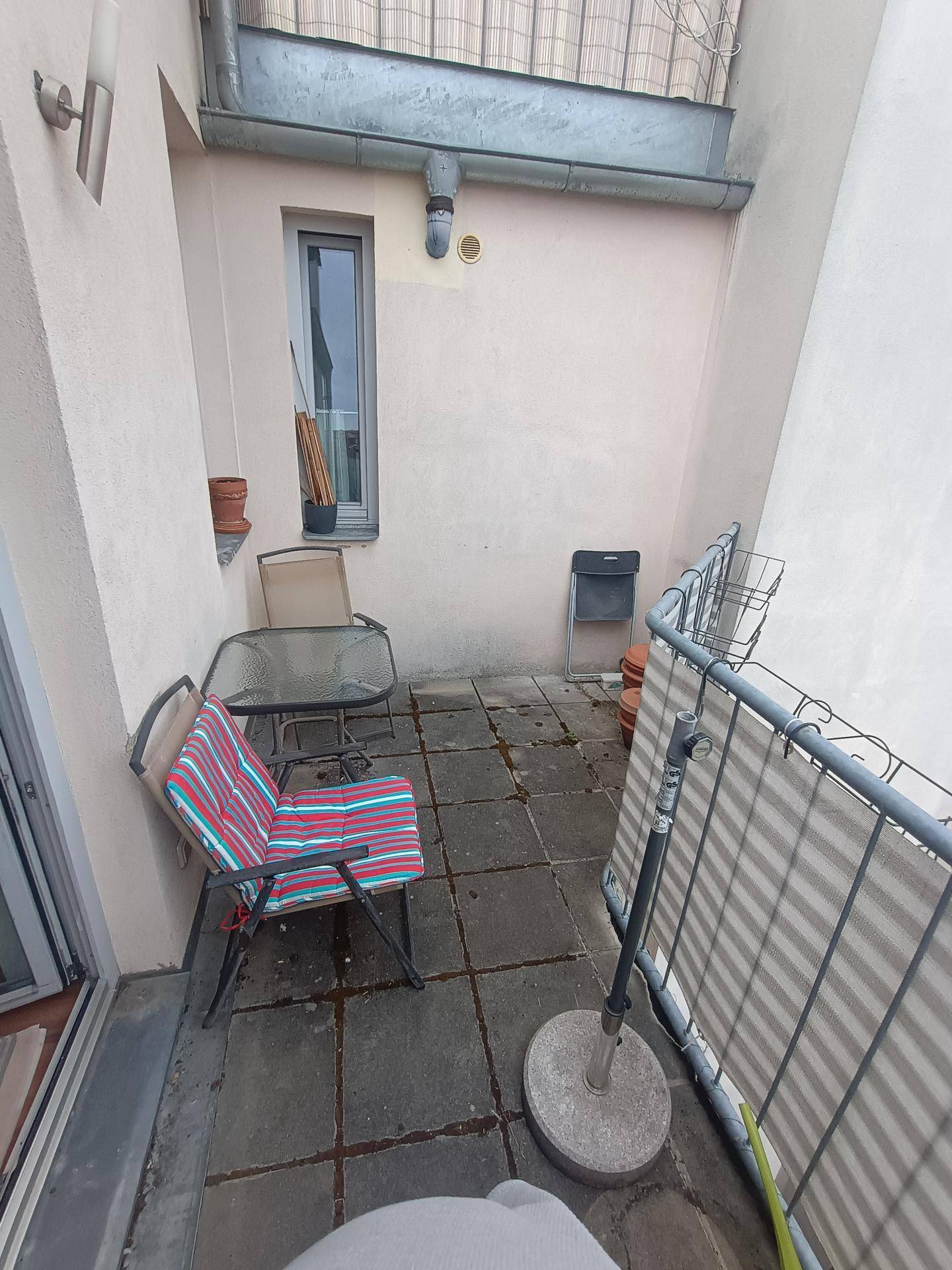 Balkon mit Steinfliesen und einfacher Sitzgruppe für entspannte Stunden im Freien.