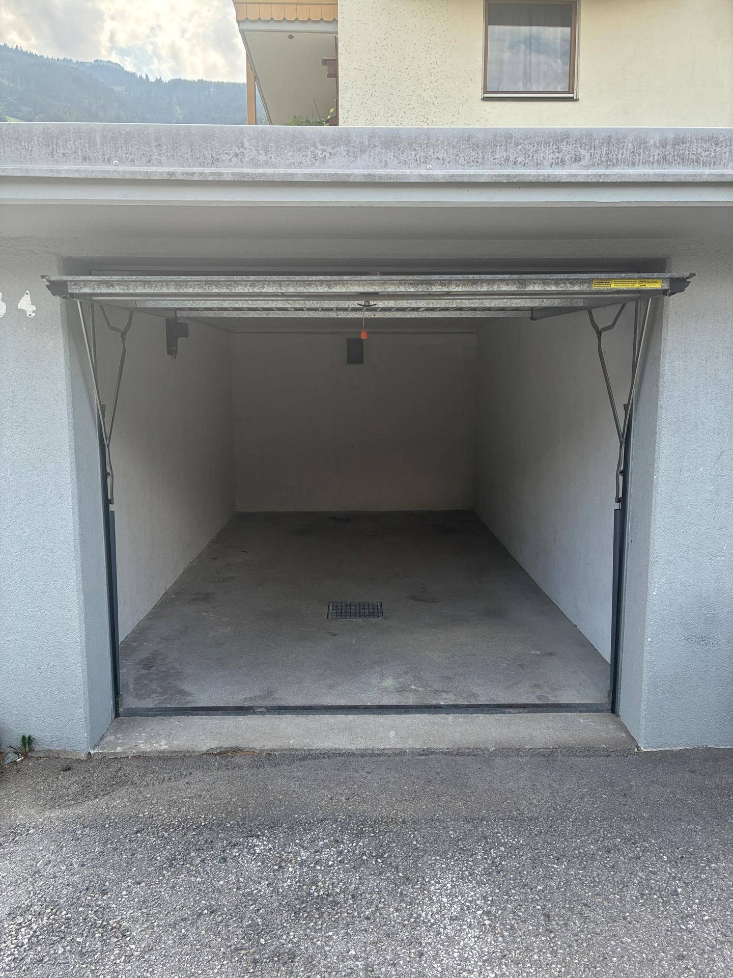 Leere Einzelgarage mit Betonboden und offenem Tor, bereit zur Nutzung als Park- oder Stauraum.