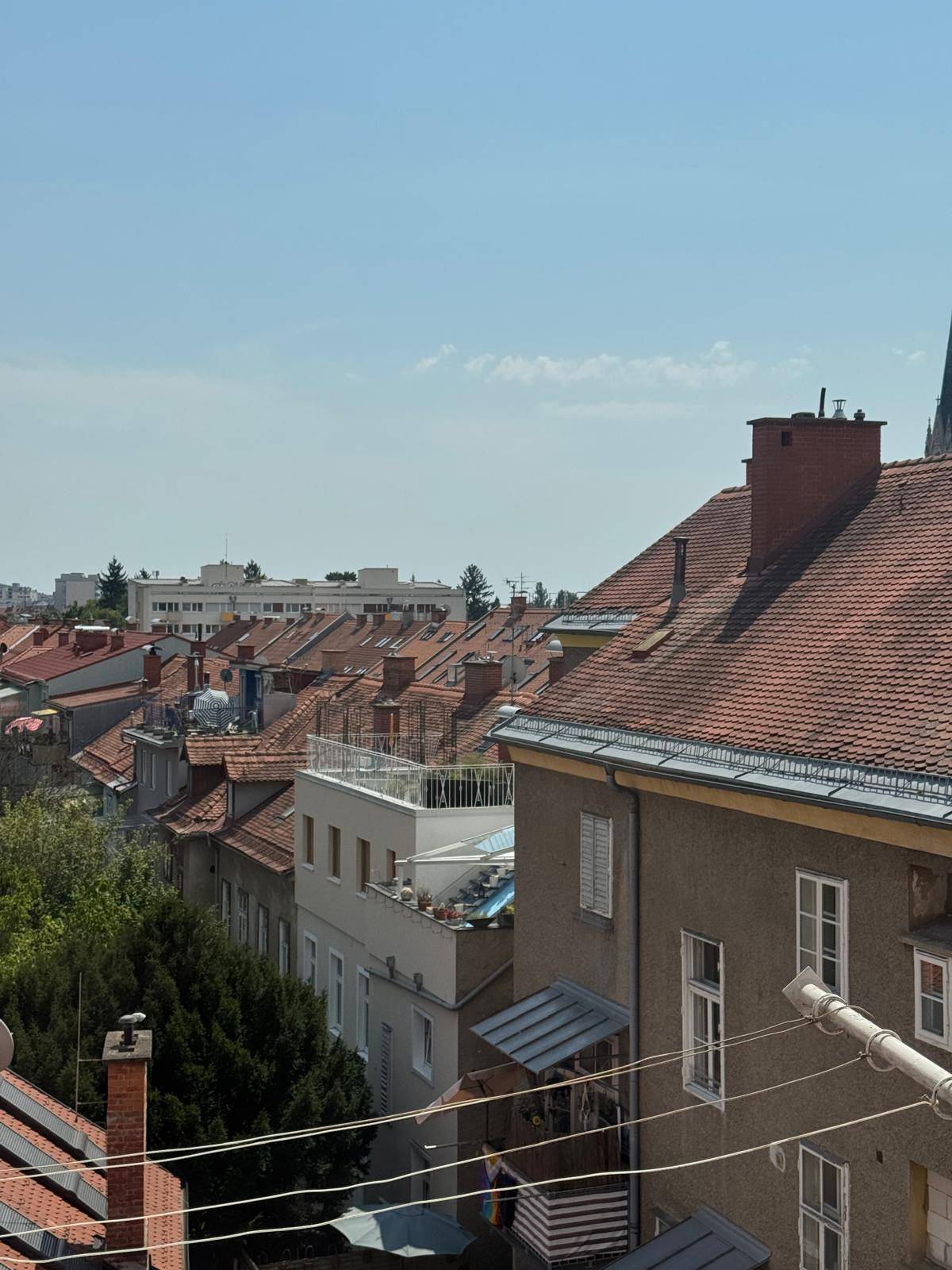Panoramablick über die Dächer der Stadt mit historischen Gebäuden und weitem Horizont unter blauem Himmel.