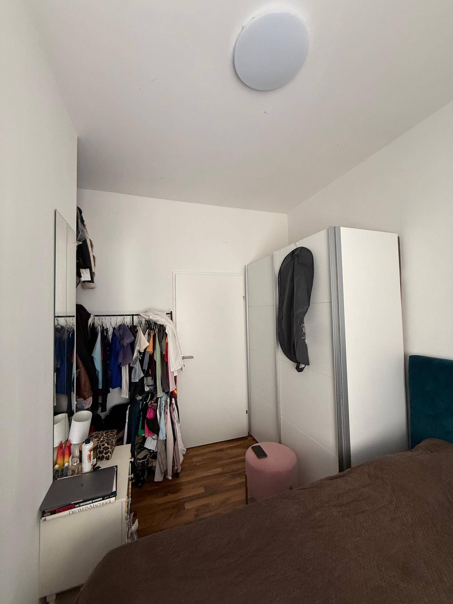 Schlafzimmer mit Kleiderstange, Spiegel und Schrank, bietet praktischen Stauraum.