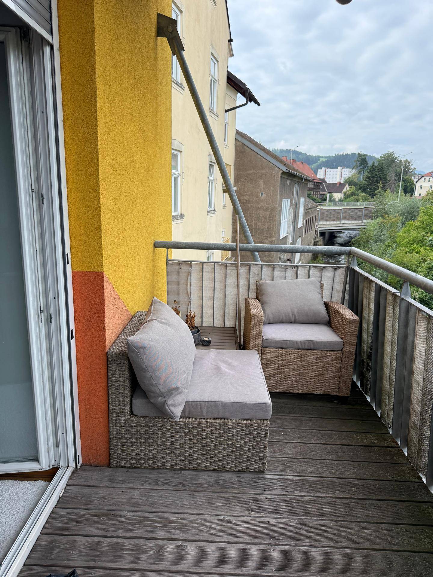 Balkon mit bequemen Sitzgelegenheiten und einer gelben Fassade, bietet einen Ausblick.