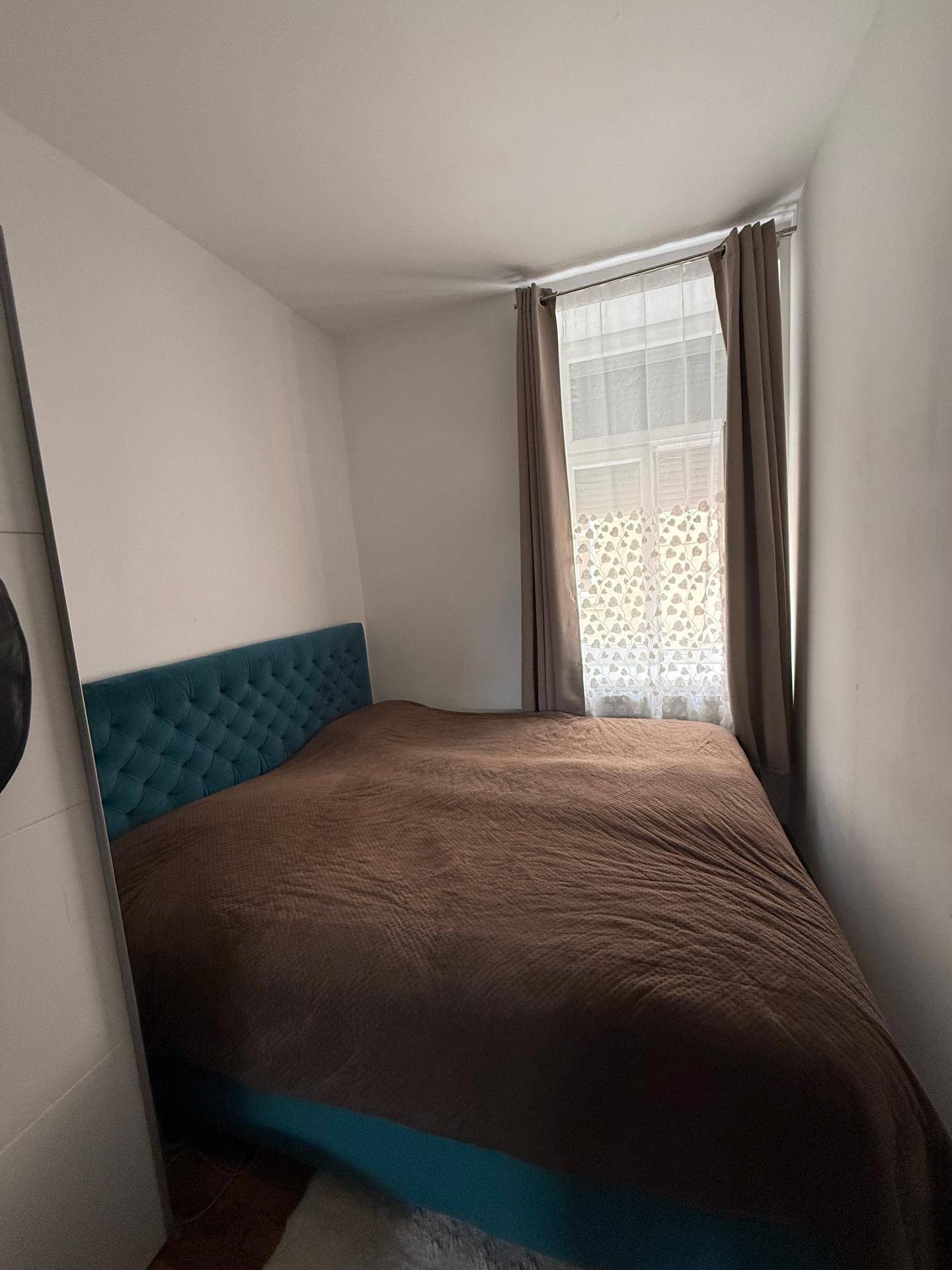 Gemütliches Schlafzimmer mit einem großen Bett und einem Fenster mit Vorhängen.