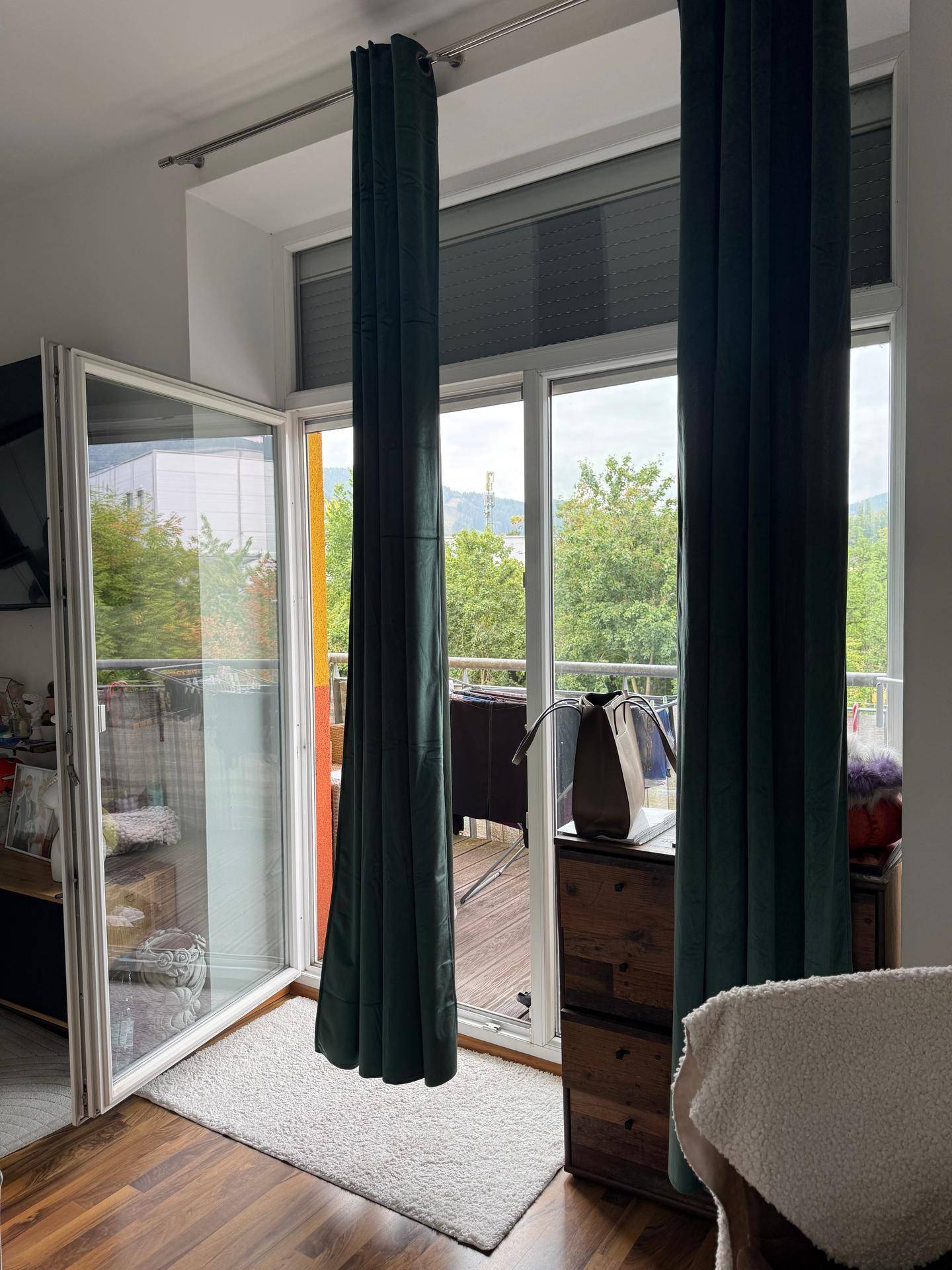 Heller Wohnbereich mit großen Fenstern und direktem Zugang zum Außenbalkon.