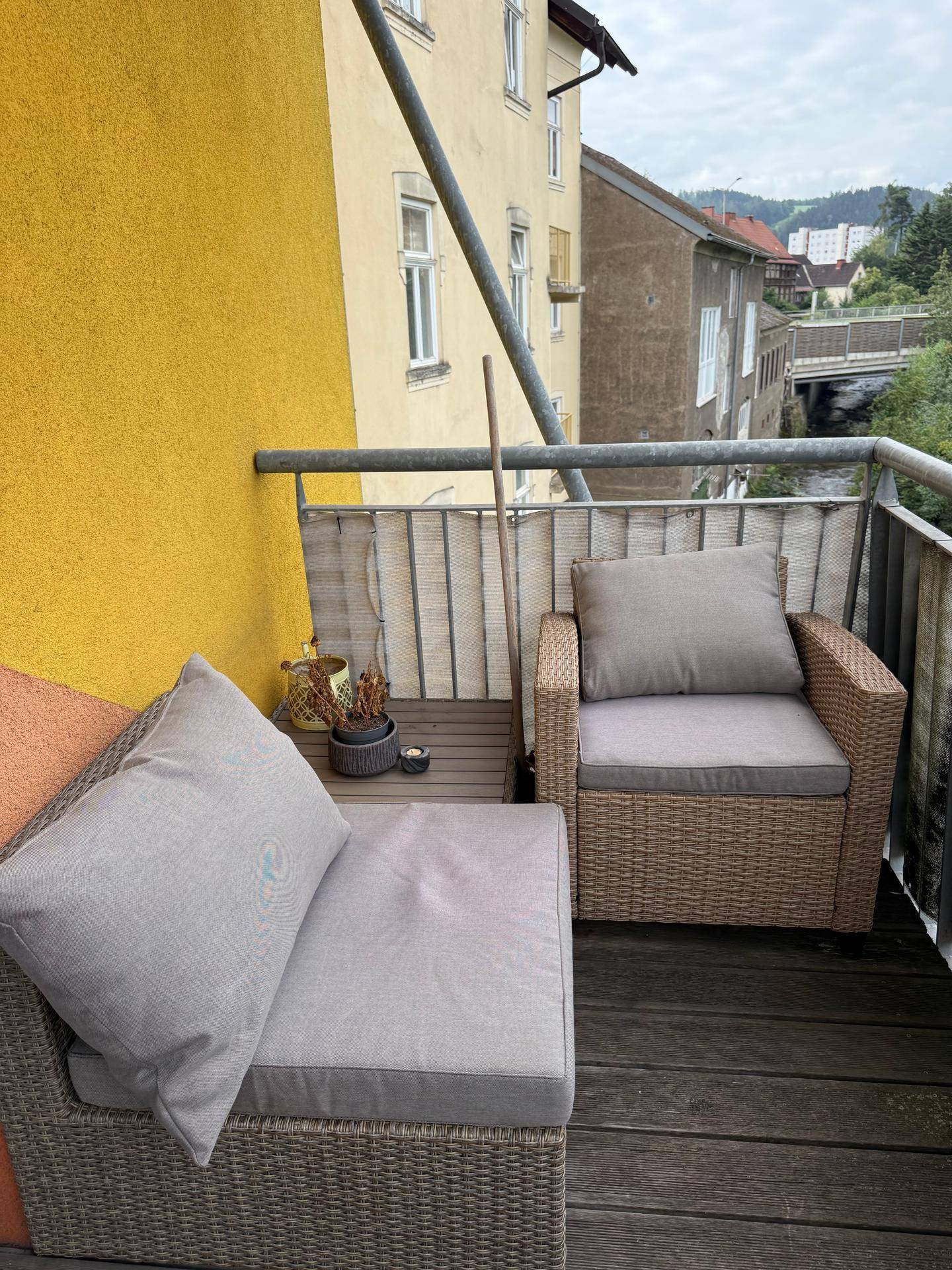 Gemütlicher Balkon mit Korbsesseln und Blick auf die umliegende Bebauung und Natur.