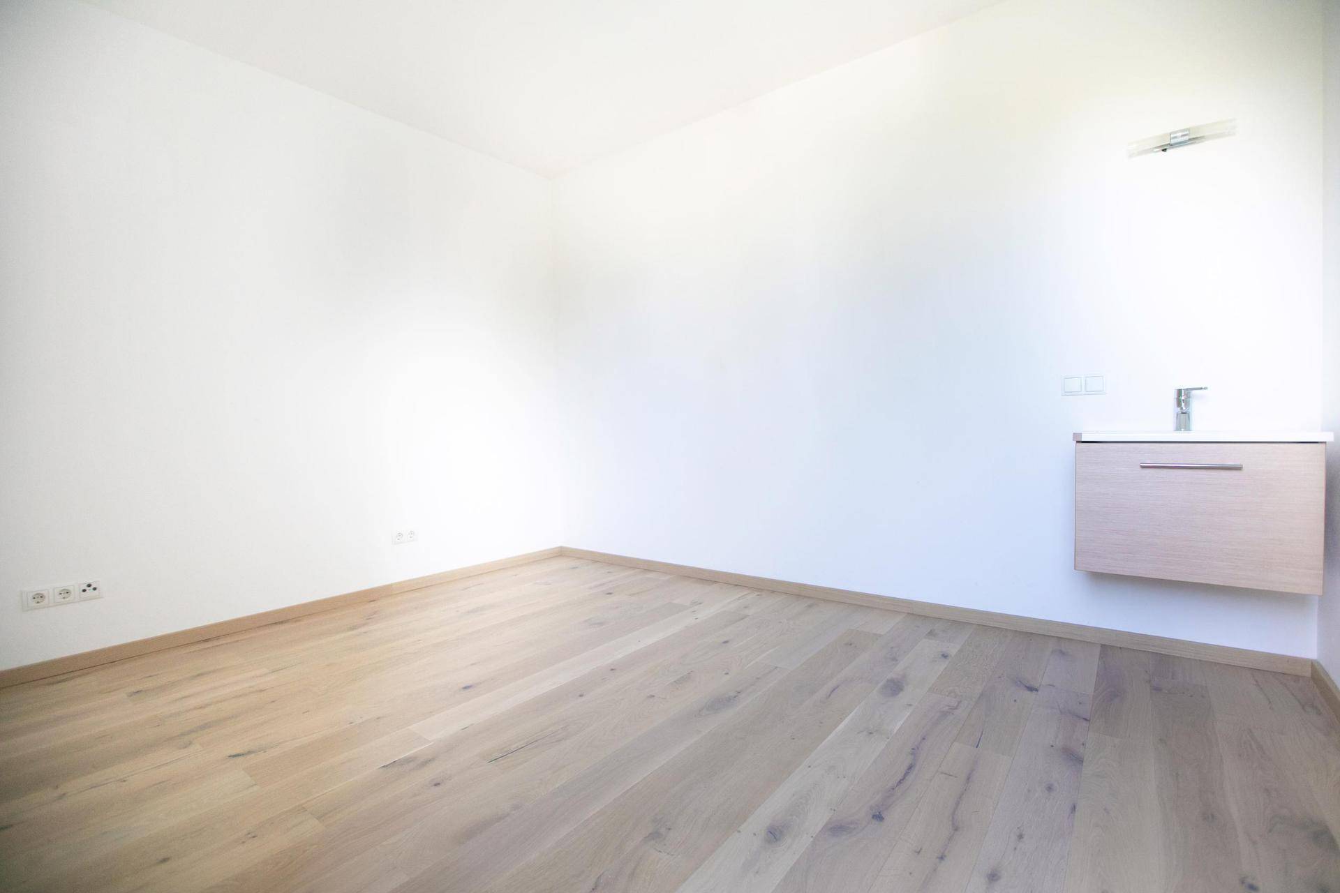 Geräumiges Zimmer mit Holzboden und einem modernen Waschbecken, das vielseitig nutzbar ist.