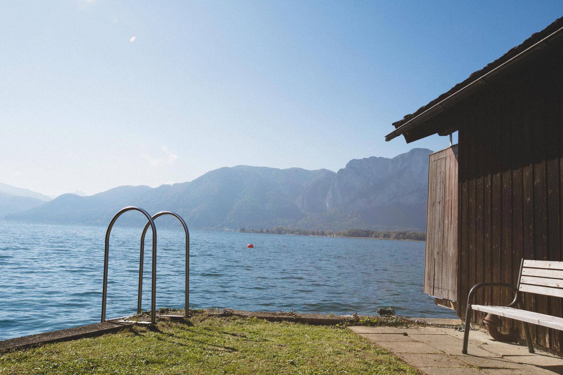 Direkter Seezugang mit einem charmanten Bootshaus und einer Bank, um die Berglandschaft zu genießen.
