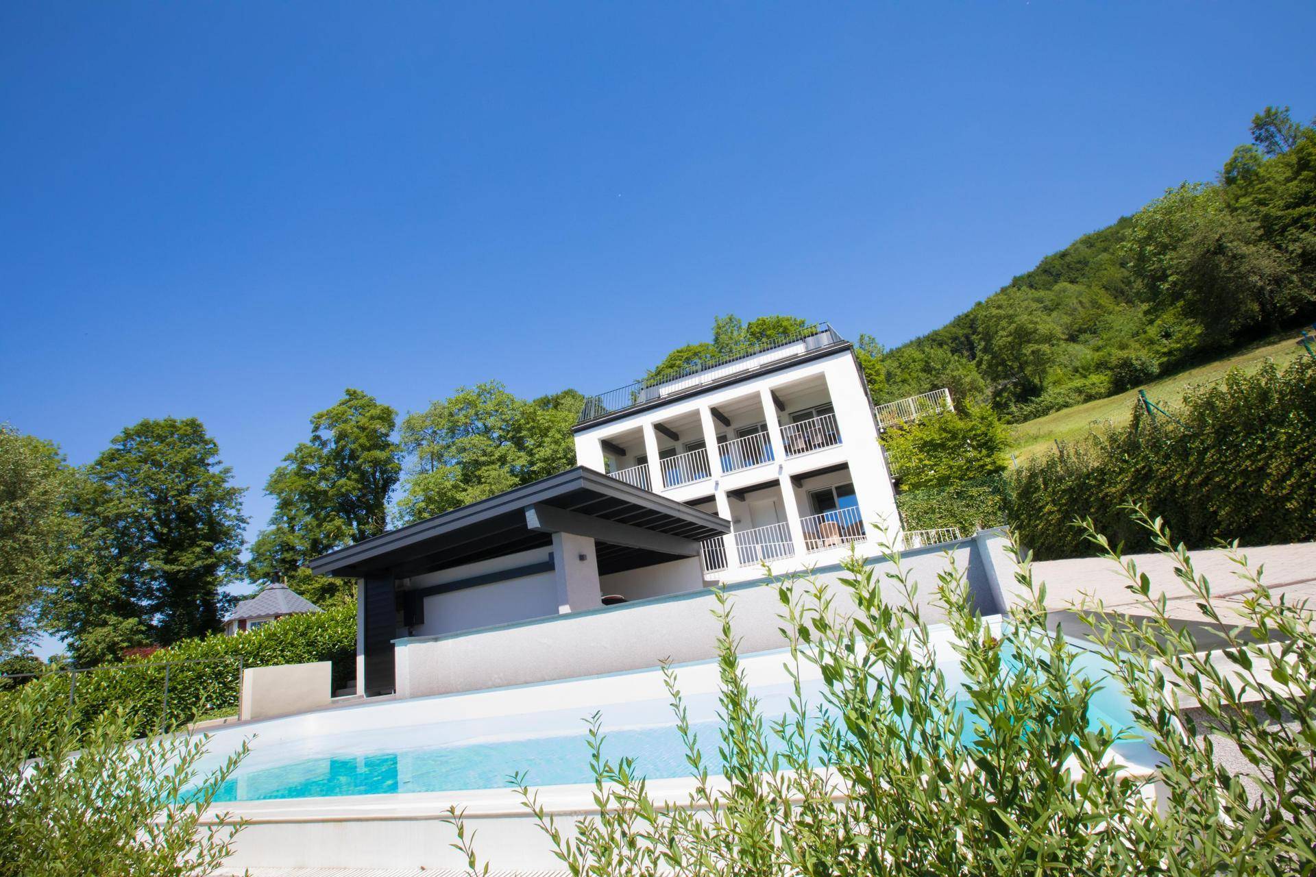 Ansicht der modernen Architektur der Villa mit Pool und der grünen Hügellandschaft im Hintergrund.