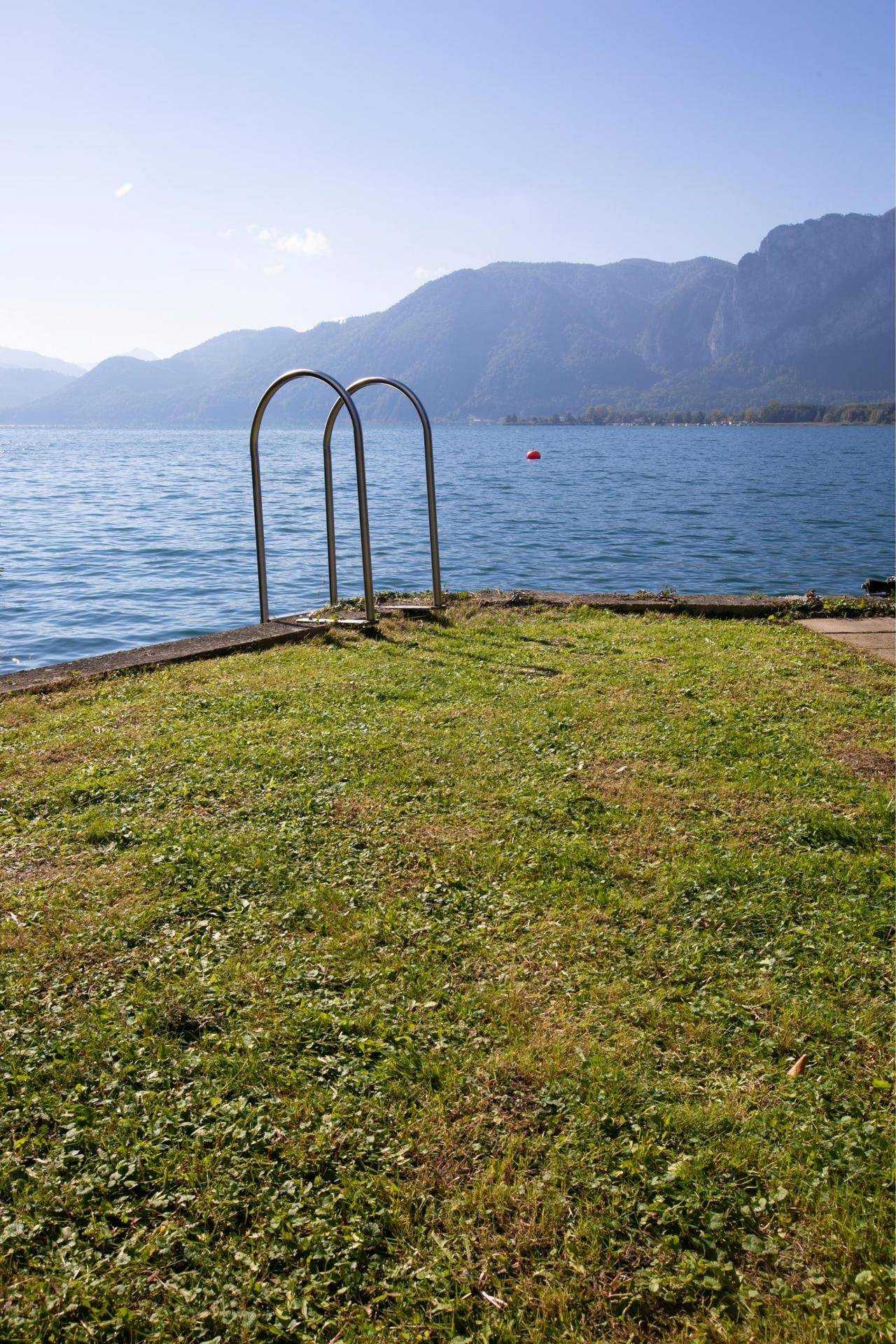 Direkter Zugang zum See mit einer kleinen Rasenfläche und einer Leiter für ein erfrischendes Bad.