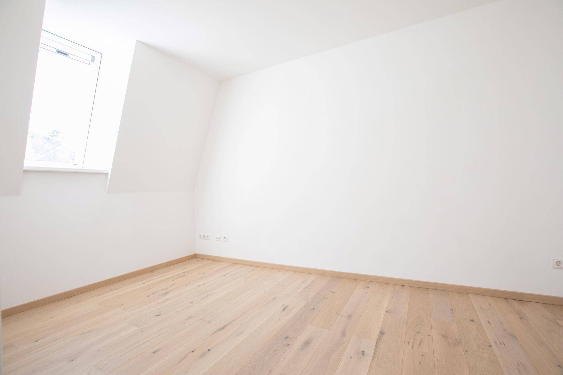 Ruhiges Zimmer mit Holzboden und einem Dachfenster, das für angenehmes Tageslicht sorgt.