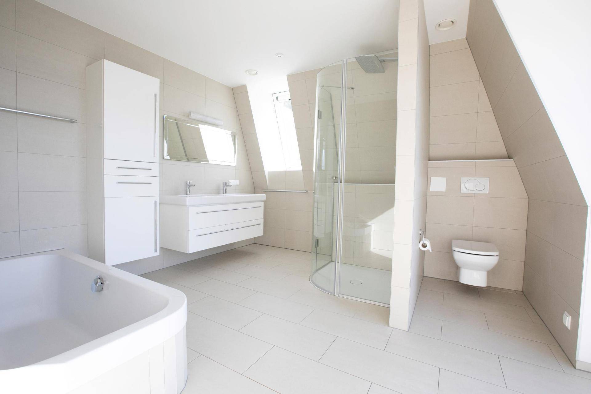 Helles Badezimmer im Dachgeschoss mit Badewanne, Dusche und modernem Doppelwaschbecken.