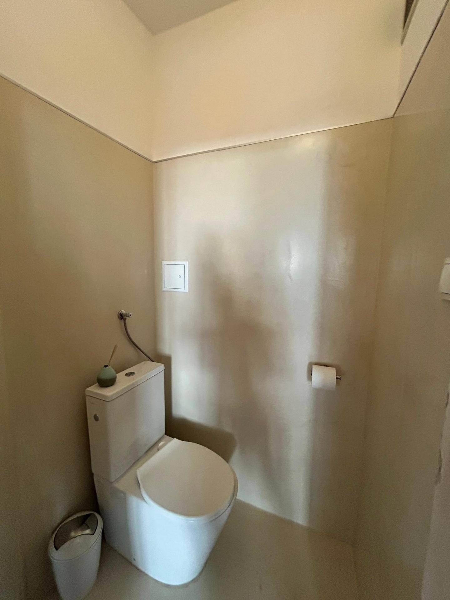 Einfaches WC mit beigefarbenen Wänden und einer Standardtoilette.