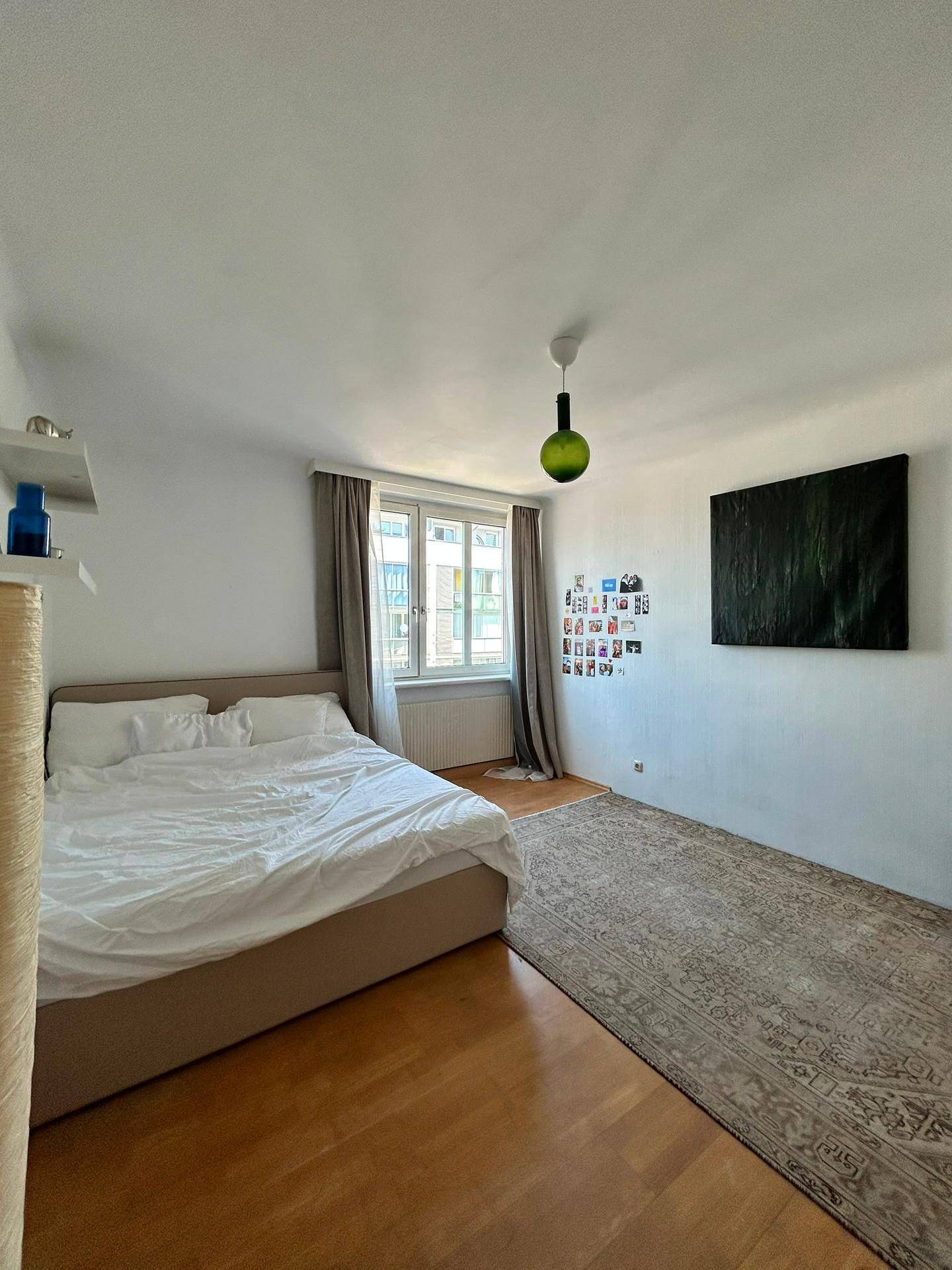 Gemütliches Schlafzimmer mit Holzboden, großem Bett und einem Fenster für natürliches Licht.