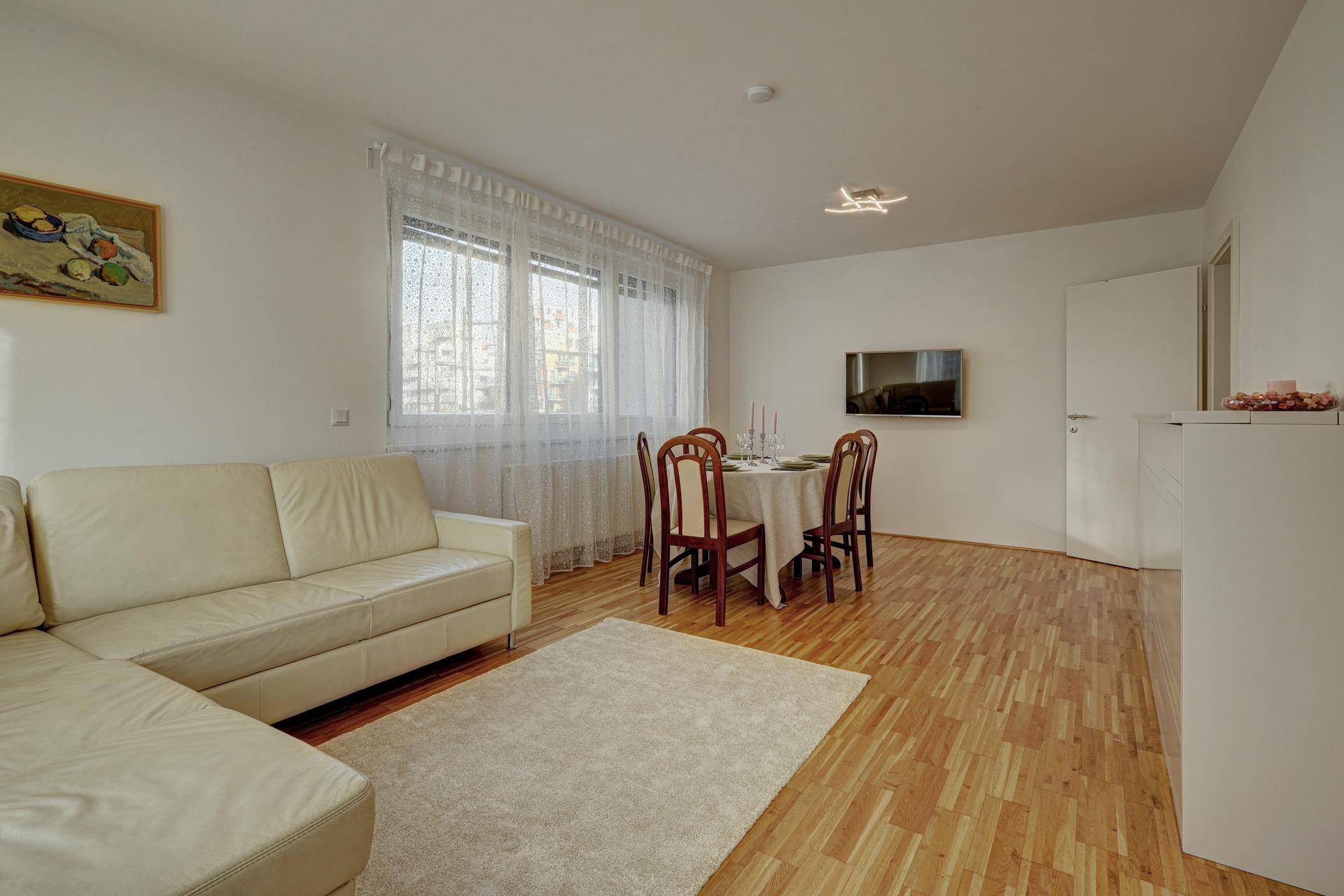 Heller Wohn-Essbereich mit Sofa, Esstisch und Holzfußboden, ideal für geselliges Beisammensein.