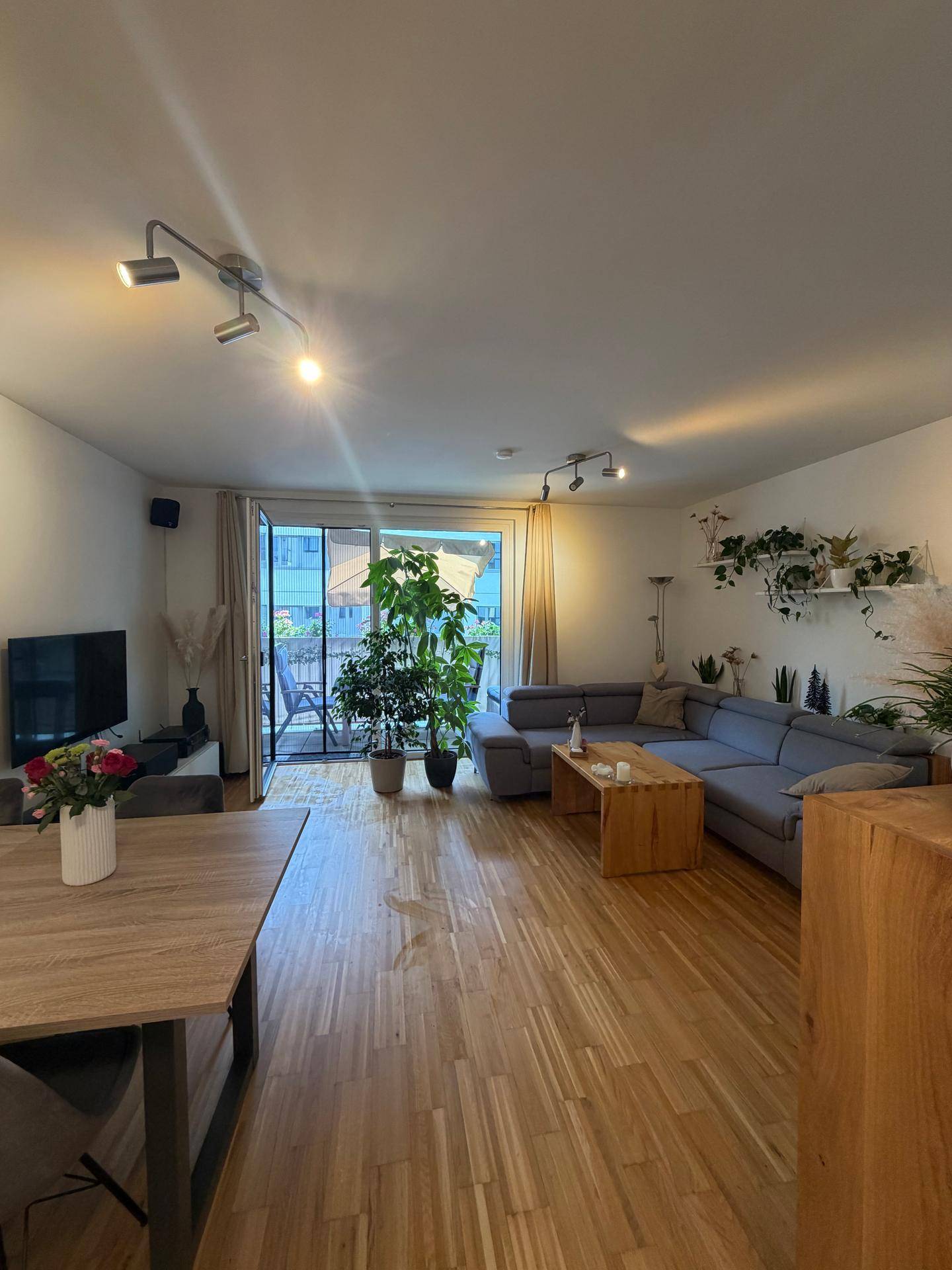 Geräumiger Wohn-Essbereich mit L-förmigem Sofa, Esstisch und direktem Zugang zum Balkon.