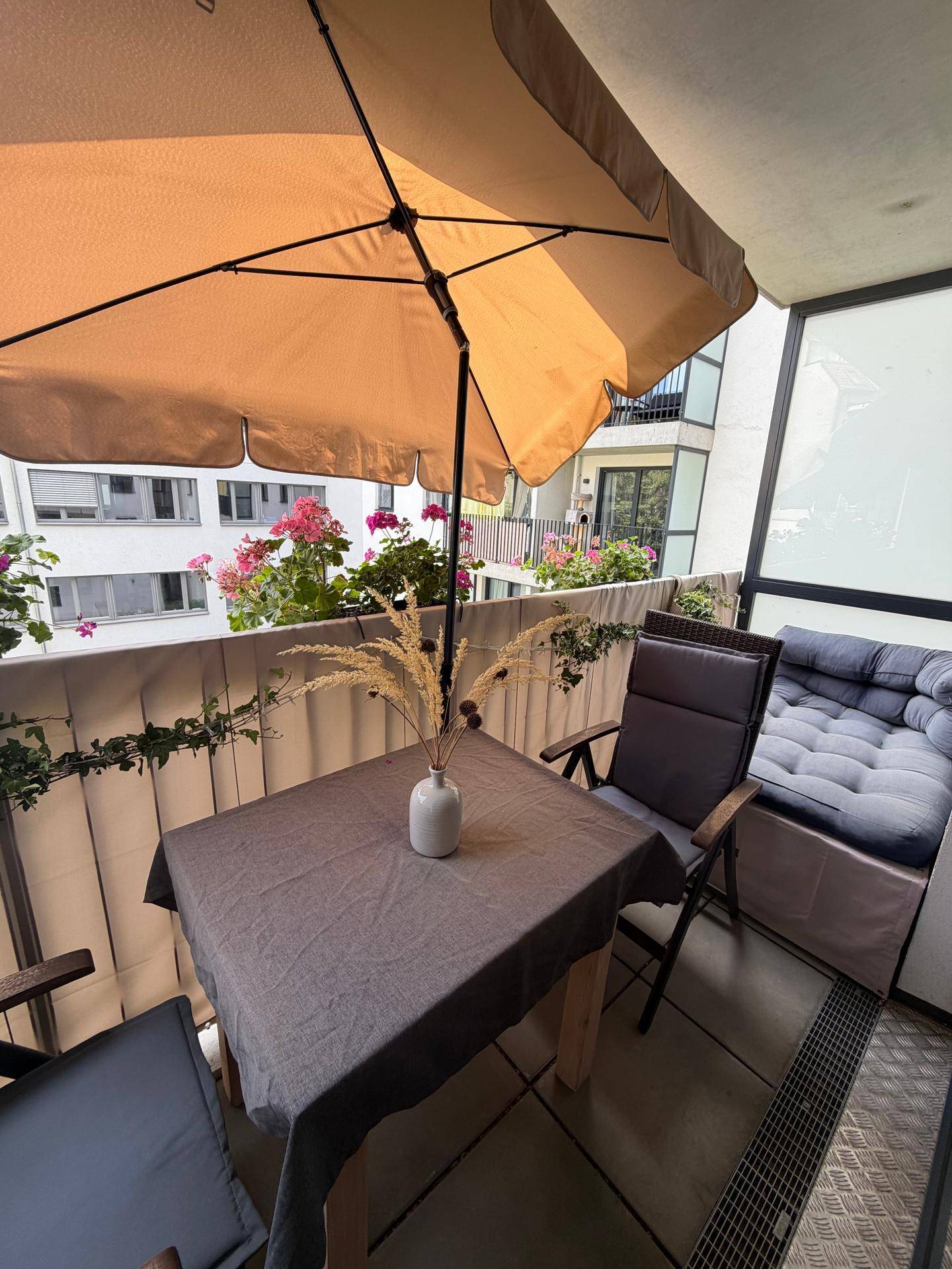 Gemütlicher Balkon mit Sitzgelegenheiten, Sonnenschirm und Blumenkästen für entspannte Stunden.