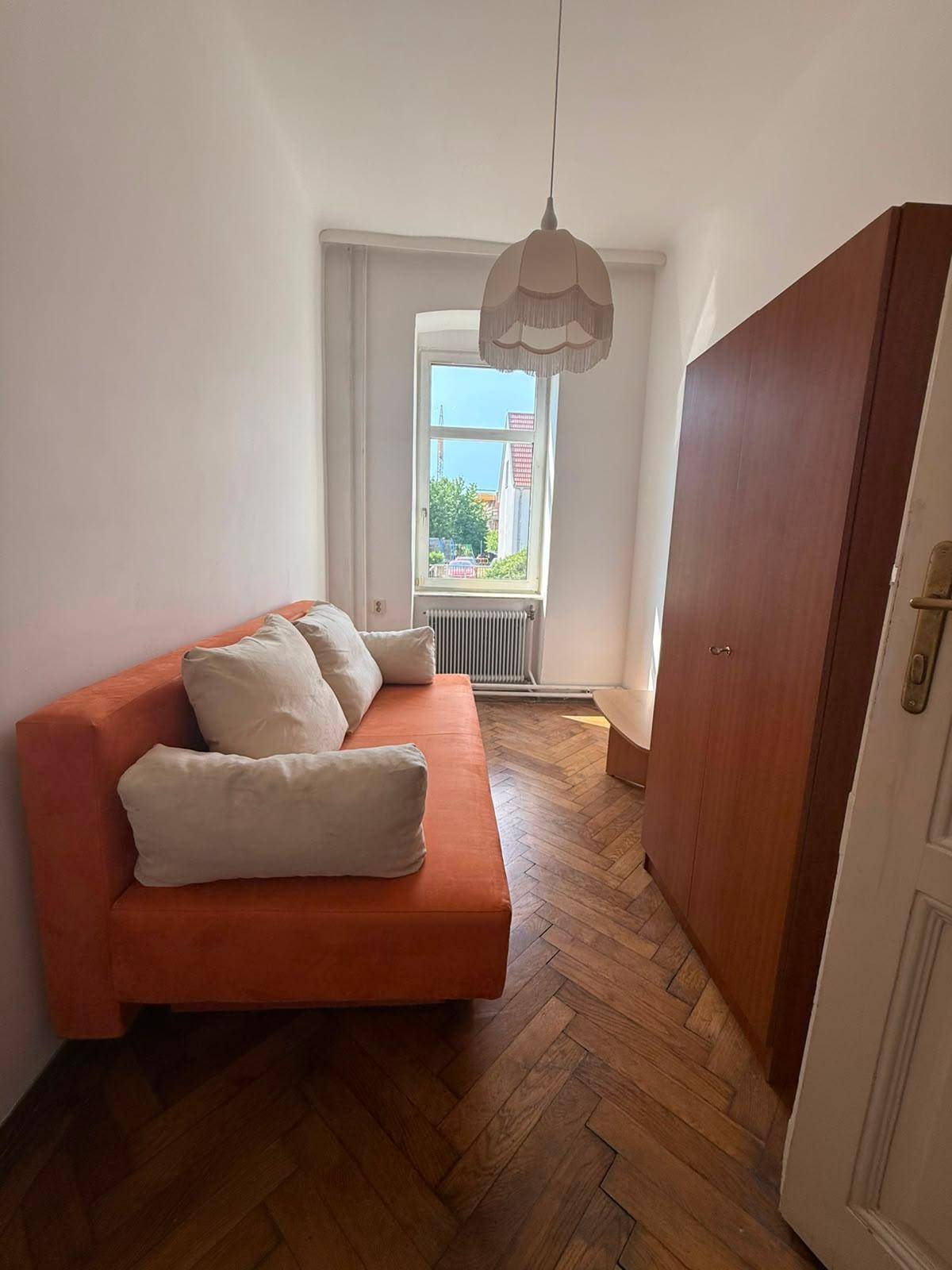 Kleines Schlafzimmer oder Gästezimmer mit Einzelbett, Holzschrank und Fischgrätparkettboden.