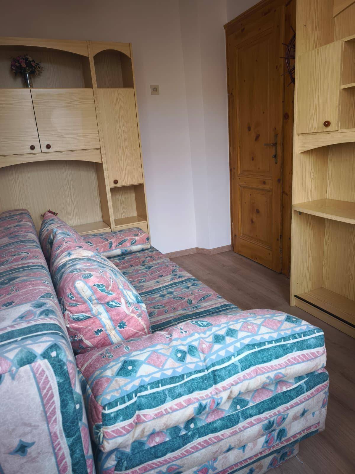 Schlafzimmer mit integrierten Holzregalen und einer Holztür, bietet praktischen Stauraum.