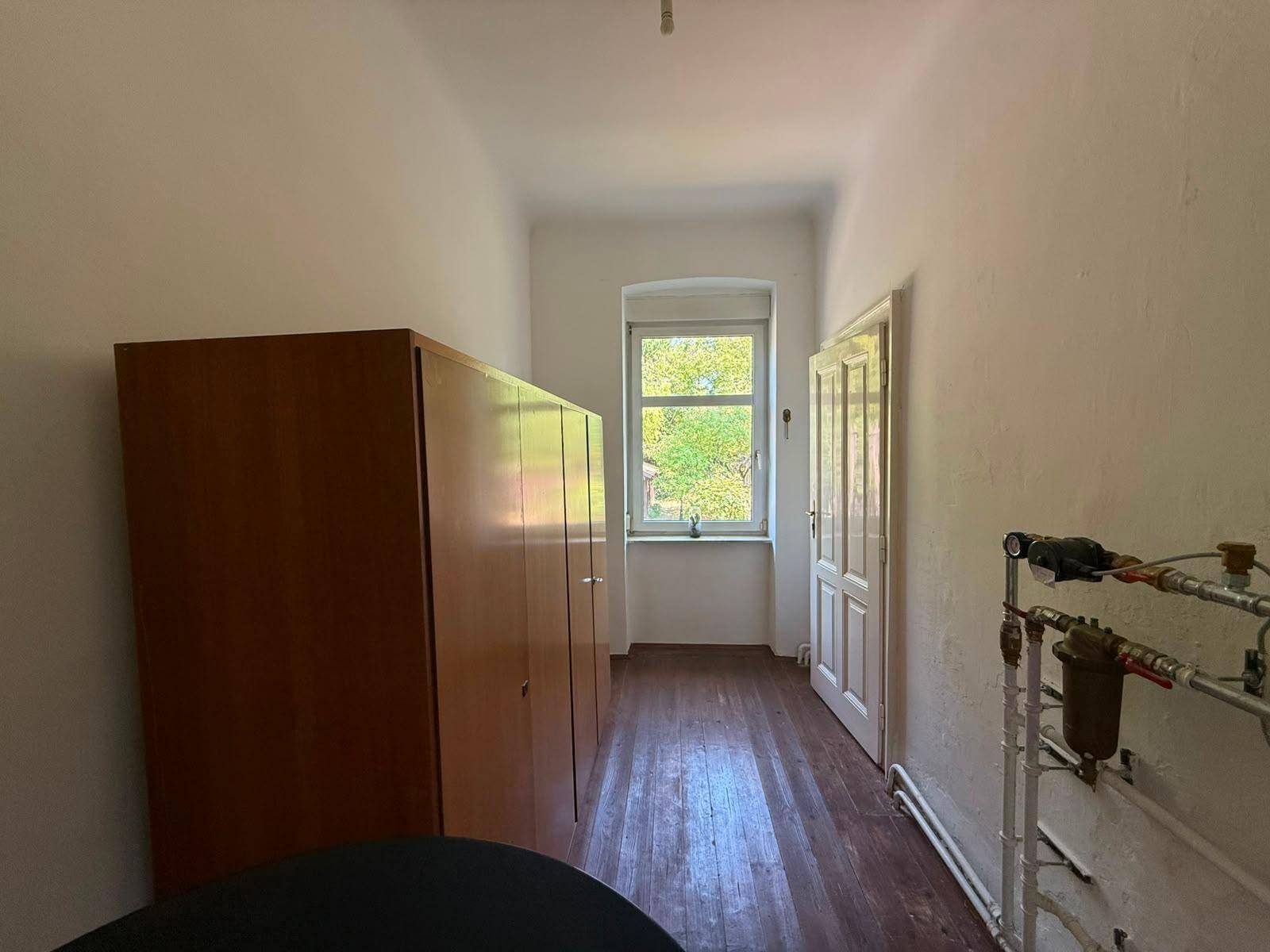 Praktischer Hauswirtschaftsraum mit großem Schrank, Fenster und sichtbaren Installationen.