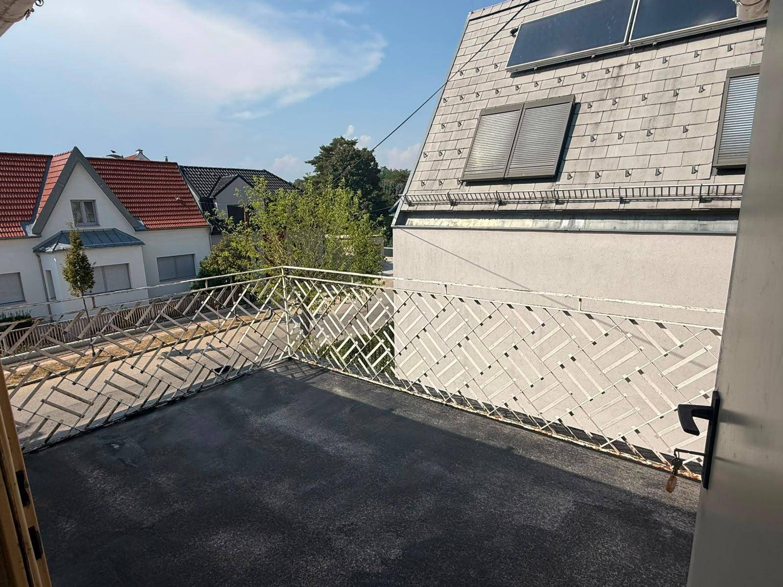Geräumiger Balkon mit Metallgeländer und Blick auf die Nachbarschaft sowie Solarpaneele.