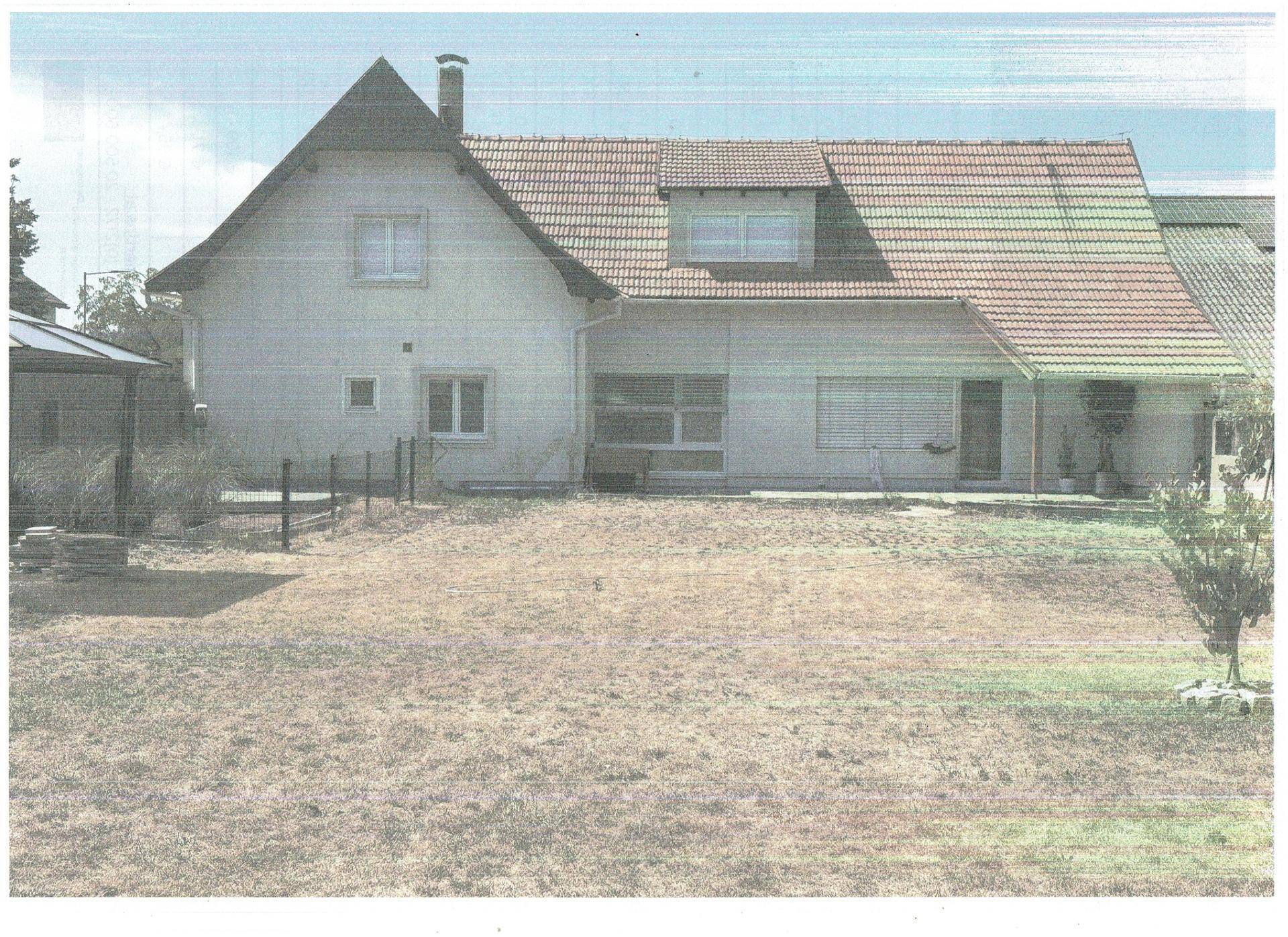 Rückansicht des Einfamilienhauses mit großem Rasenbereich und Rollläden an den Fenstern.