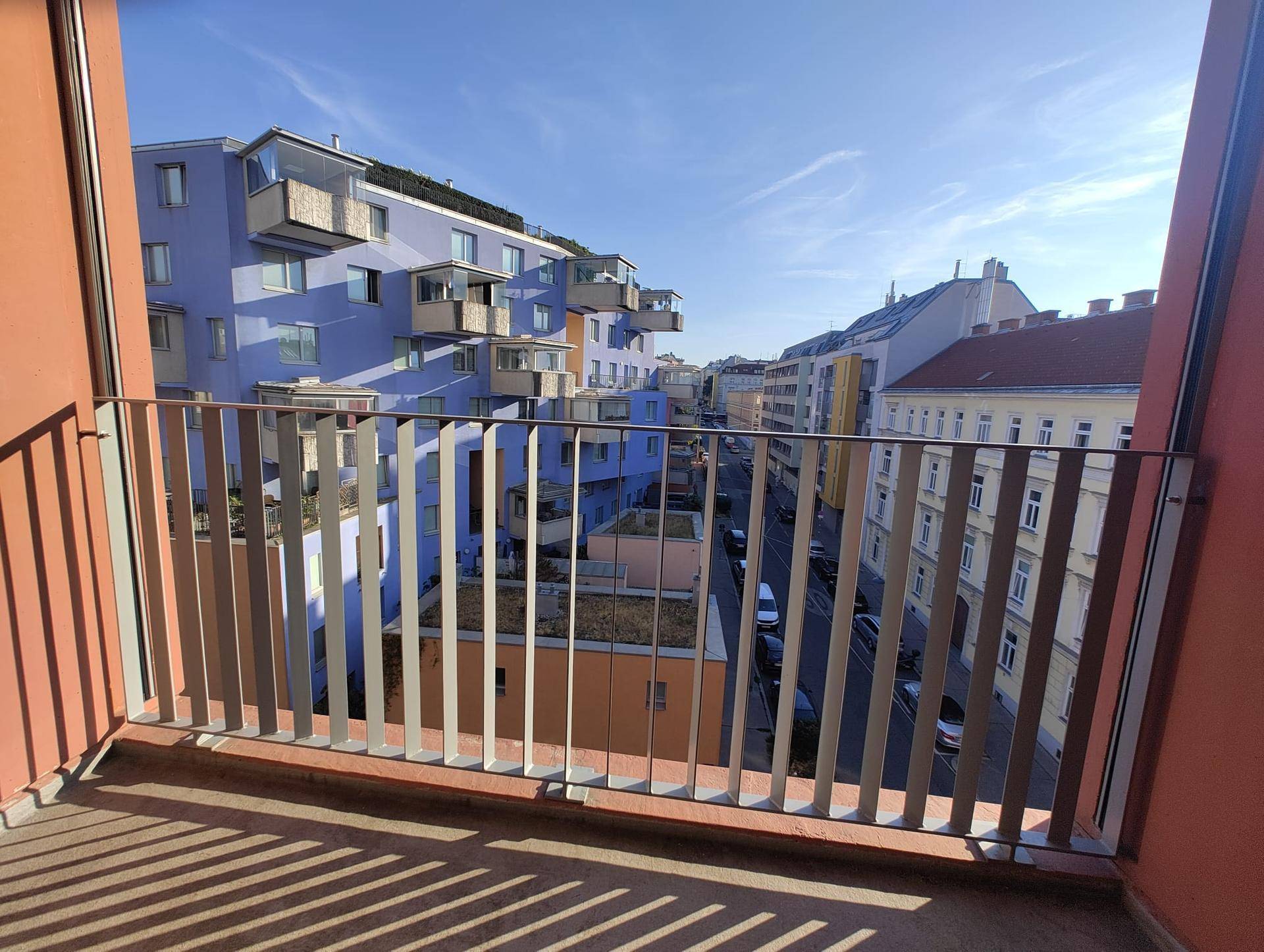 Balkon mit weitem Blick auf eine belebte Straße und farbenfrohe Gebäude in der Stadt.