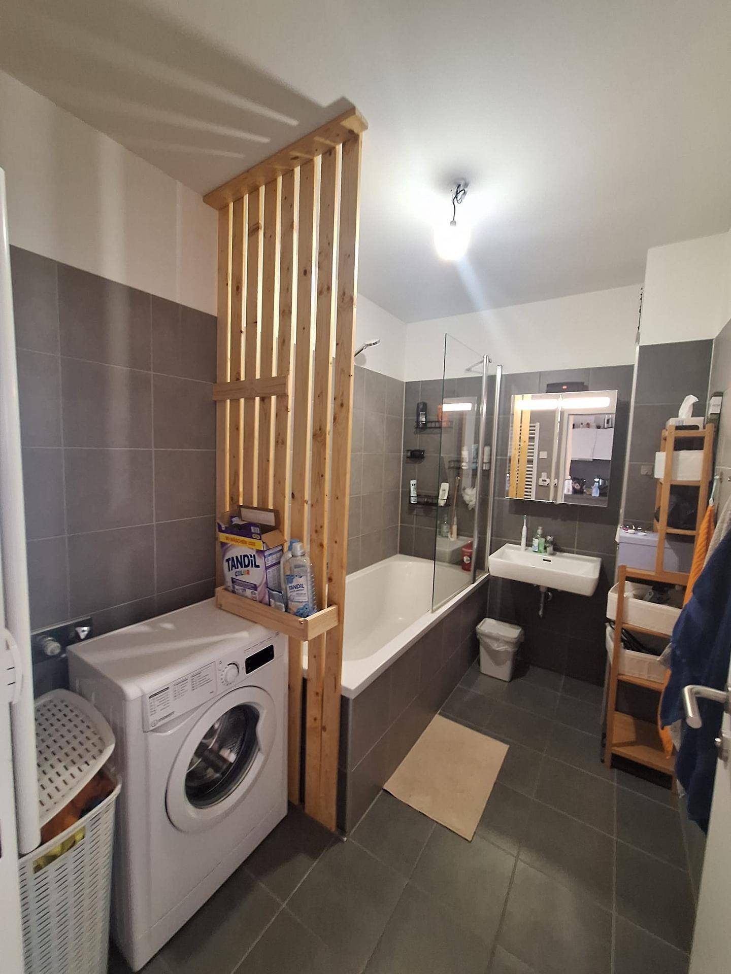 Modernes Badezimmer mit Badewanne, Duschabtrennung, Waschbecken und Waschmaschine.