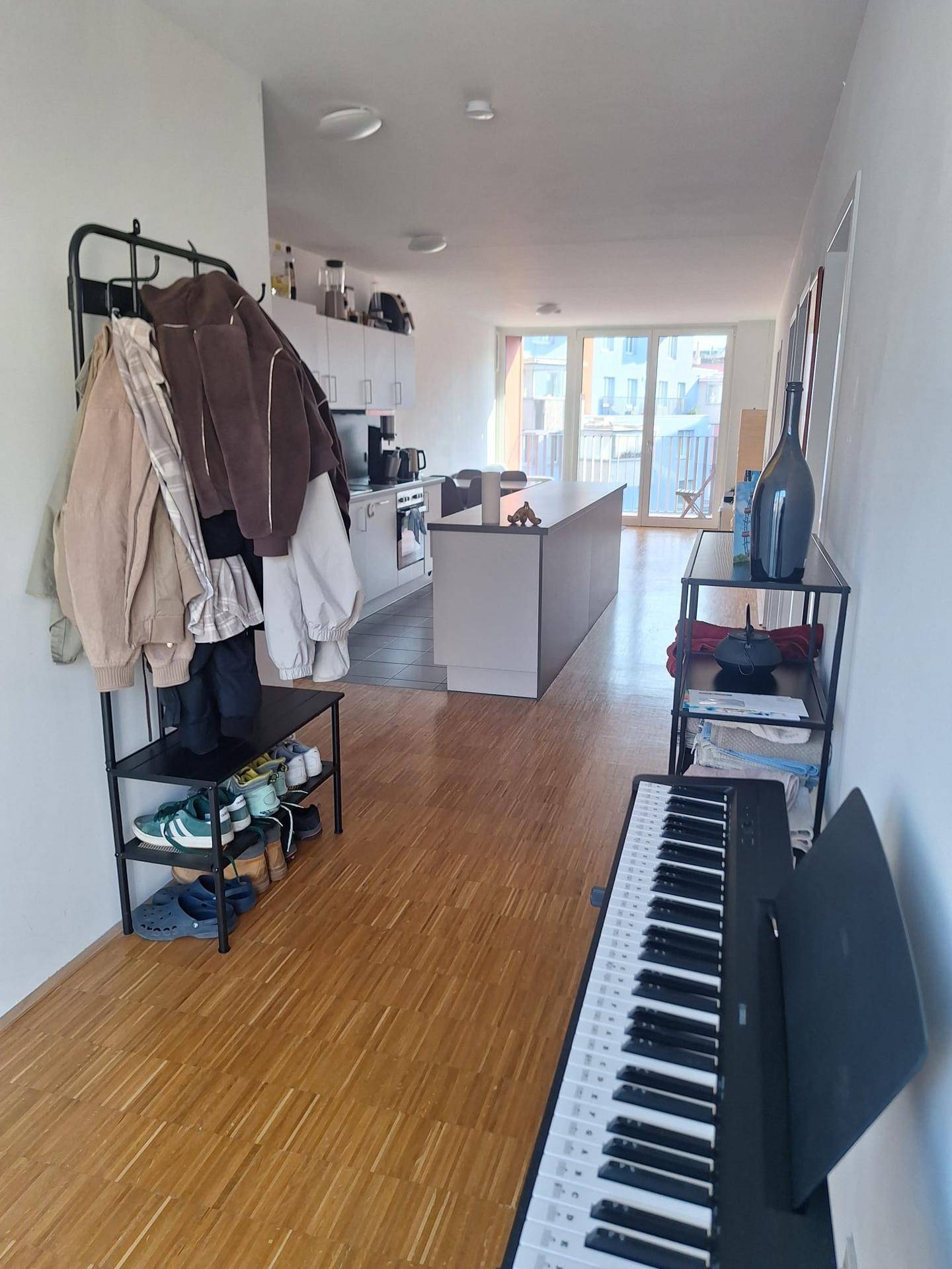 Eingangsbereich mit Garderobe und Klavier, der in den offenen Wohnbereich führt.