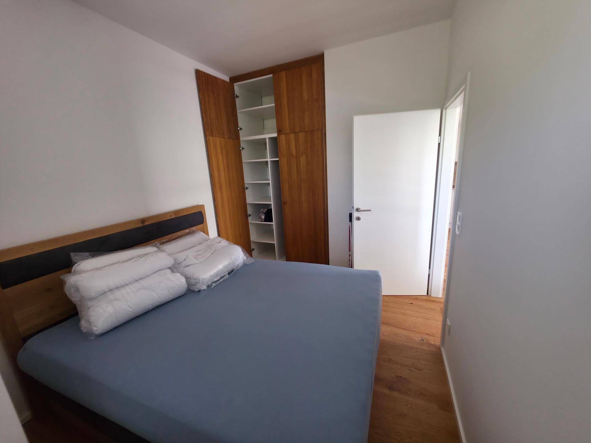 Schlafzimmer mit Holzbett, integriertem Kleiderschrank und hellem Holzboden.