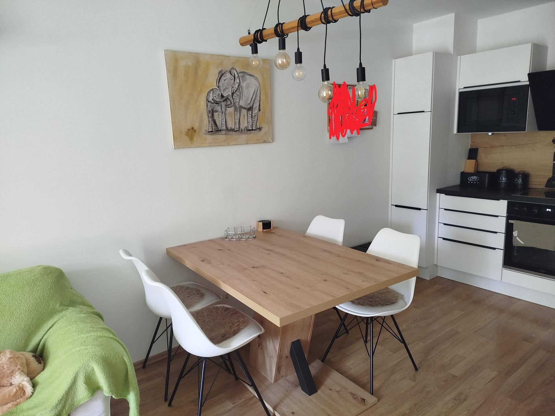 Offener Wohn- und Essbereich mit Holztisch und moderner Küche im Hintergrund, ideal für Geselligkeit.