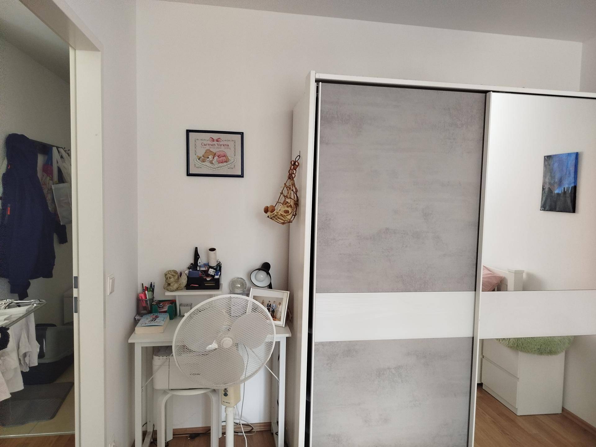 Kleiner Arbeitsbereich mit Schreibtisch und modernem Kleiderschrank mit Schiebetüren im Schlafzimmer integriert.