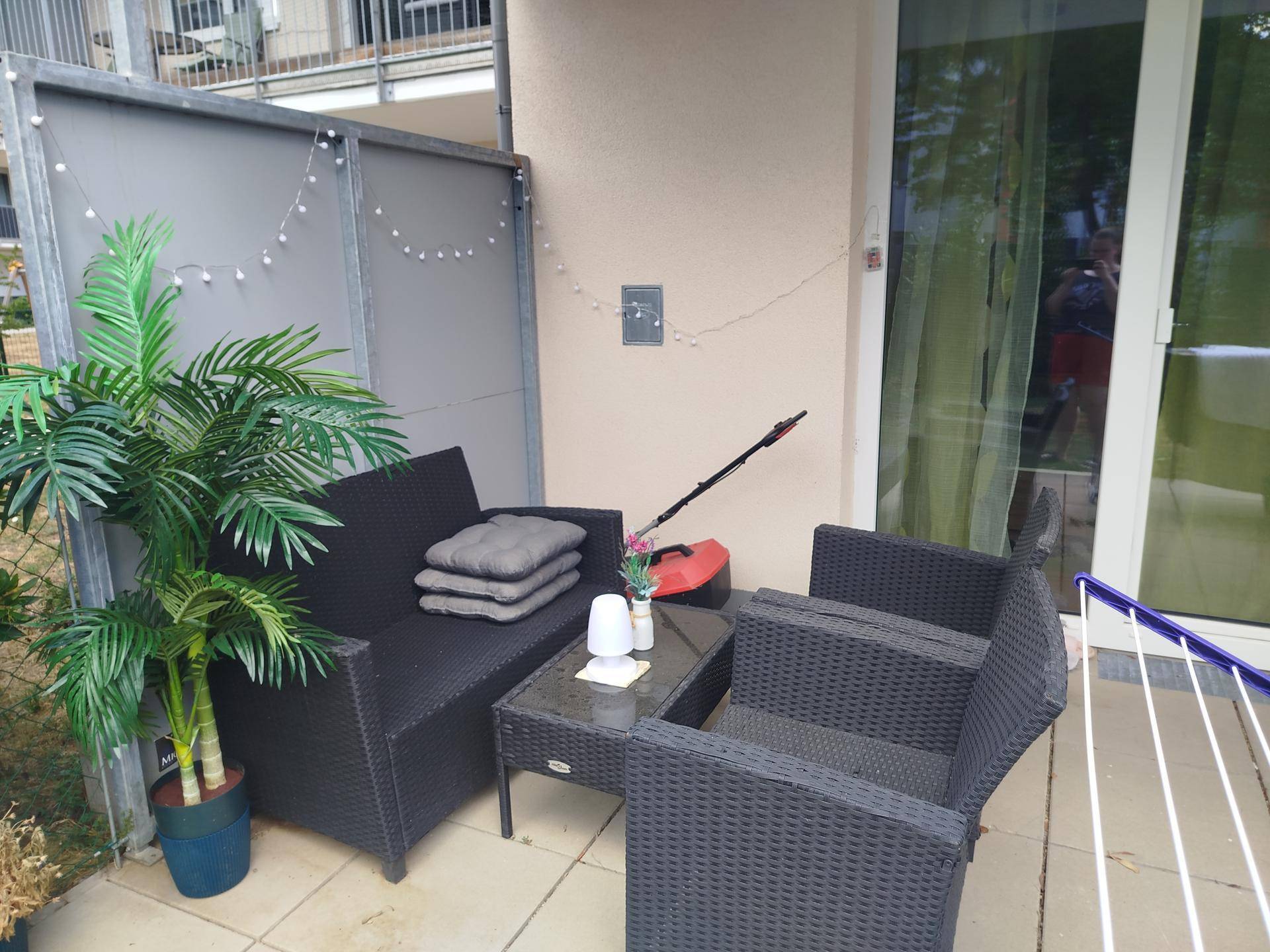 Gemütliche Terrasse mit Rattanmöbeln, Pflanzen und dekorativer Beleuchtung für entspannte Abende im Freien.