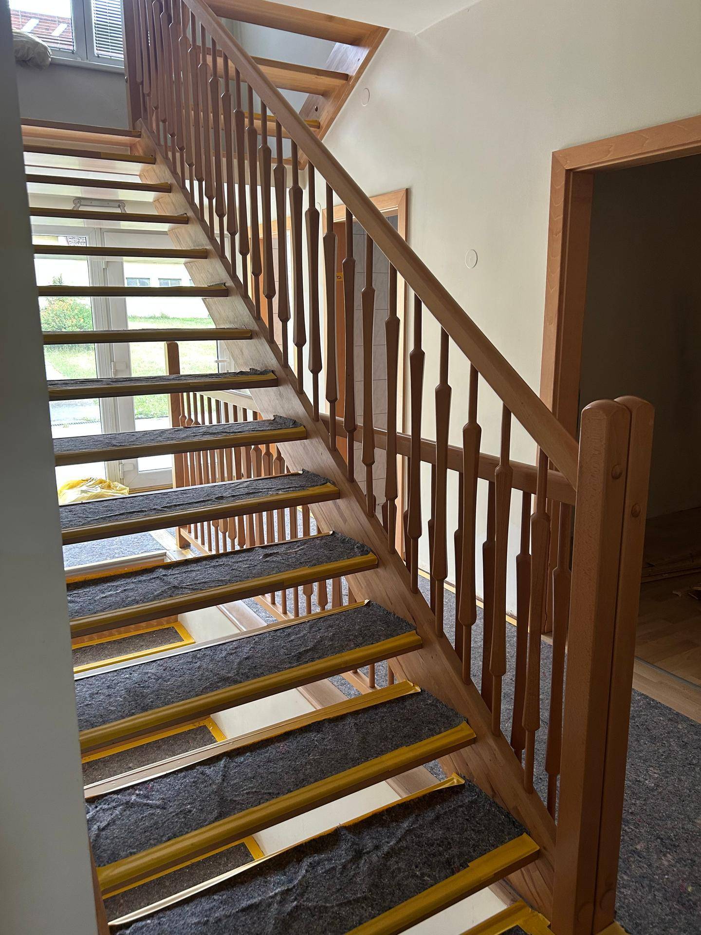 Elegante Holztreppe mit Geländer, die in ein helles Obergeschoss führt und gut gepflegt ist.
