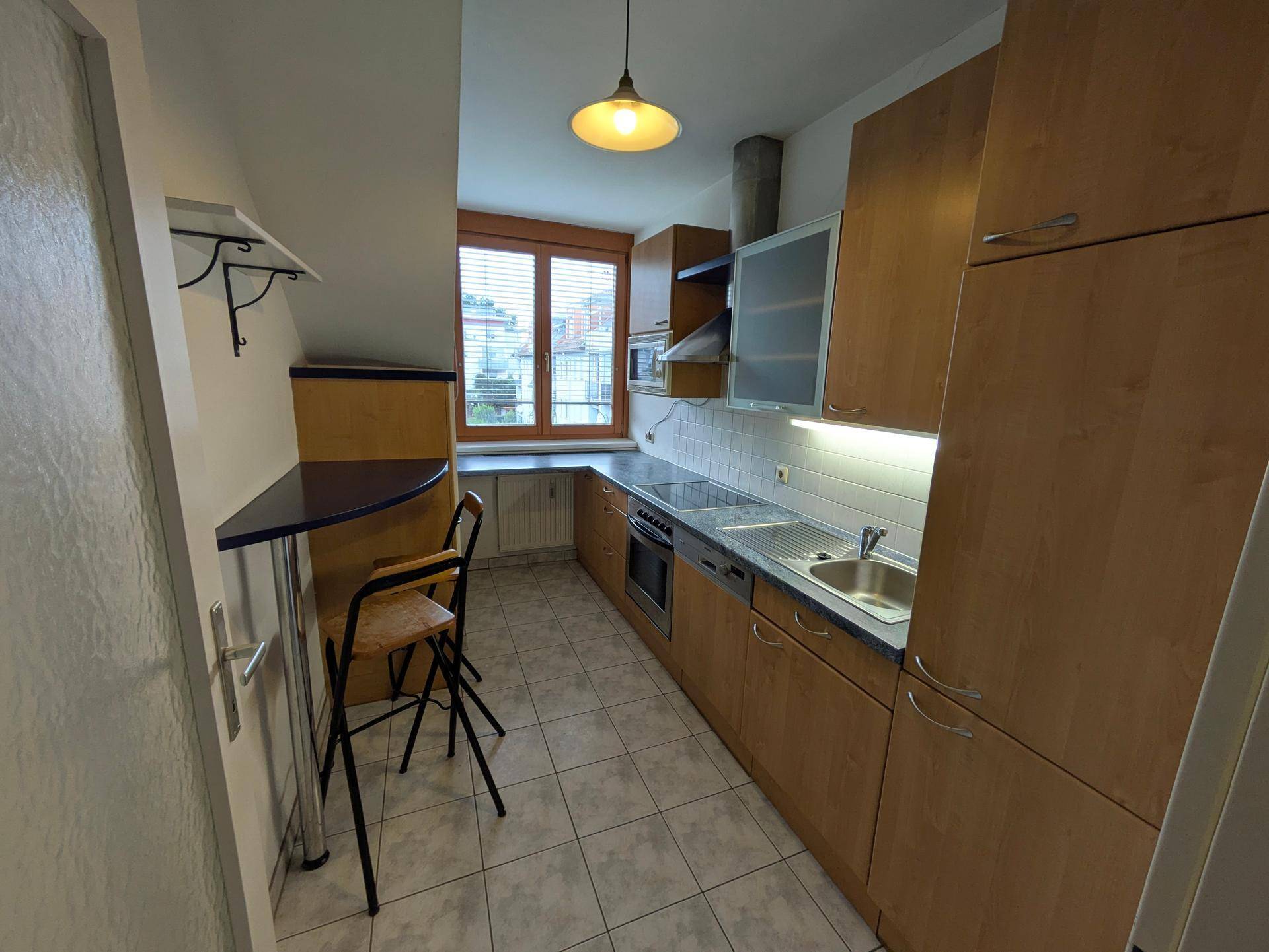 Gut ausgestattete Küche mit Holzfronten, integrierten Geräten und einem kleinen Bartisch.