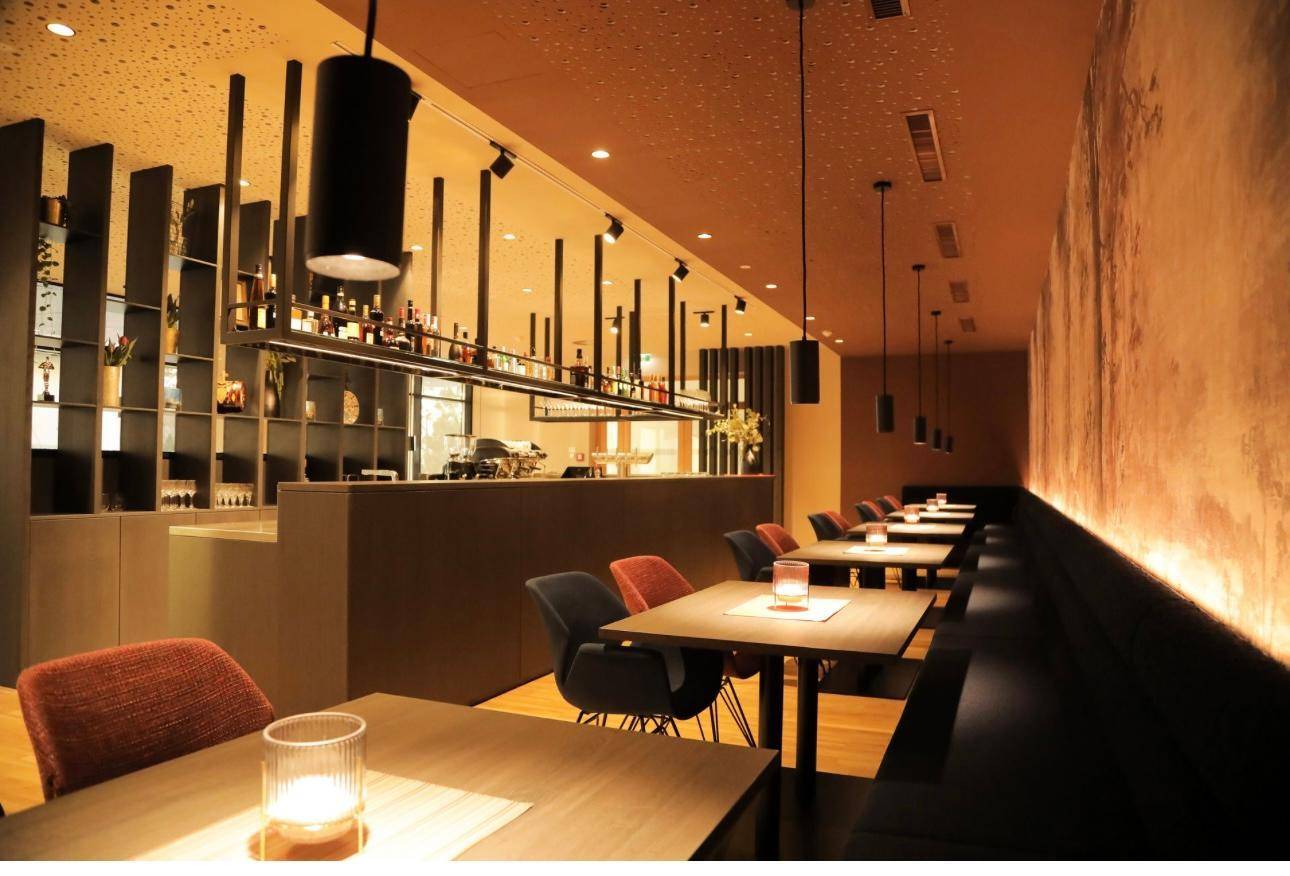 Weitläufiger Restaurant- und Barbereich mit verschiedenen Sitzgelegenheiten, einer langen Theke und stimmungsvoller Beleuchtung.