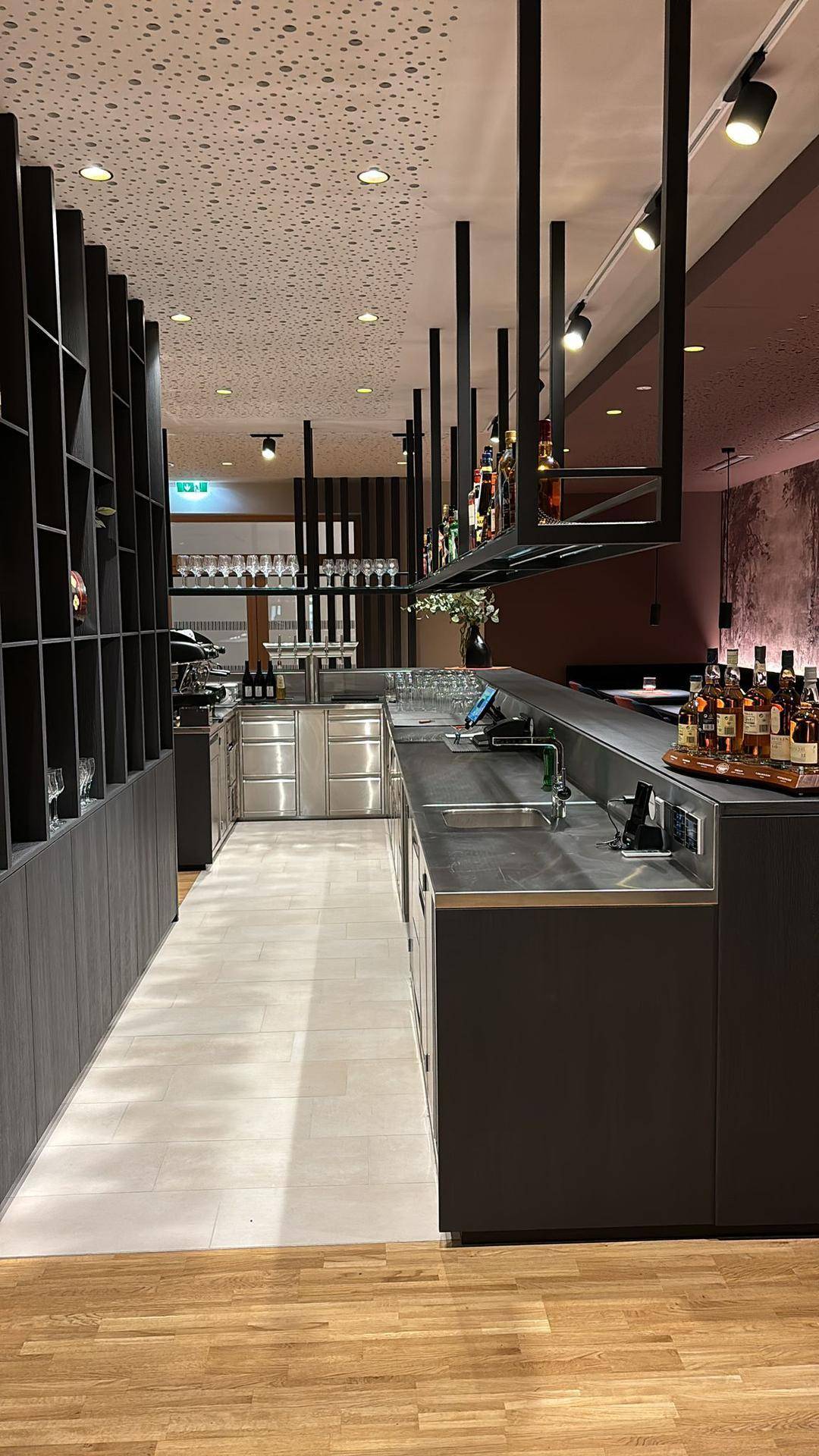 Professionelle Servicetheke mit Edelstahloberflächen und modernen Geräten, angrenzend an den Barbereich.
