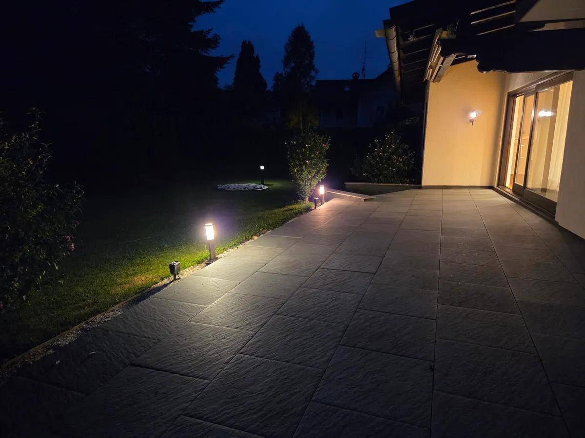 Beleuchtete Terrasse und Gartenbereich bei Nacht mit stimmungsvoller Wegbeleuchtung.