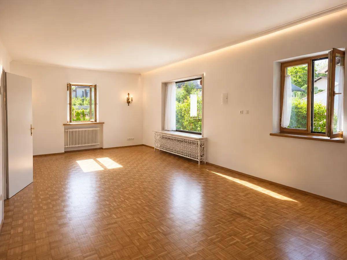 Heller Raum mit Parkettboden, mehreren Fenstern und viel Tageslicht.
