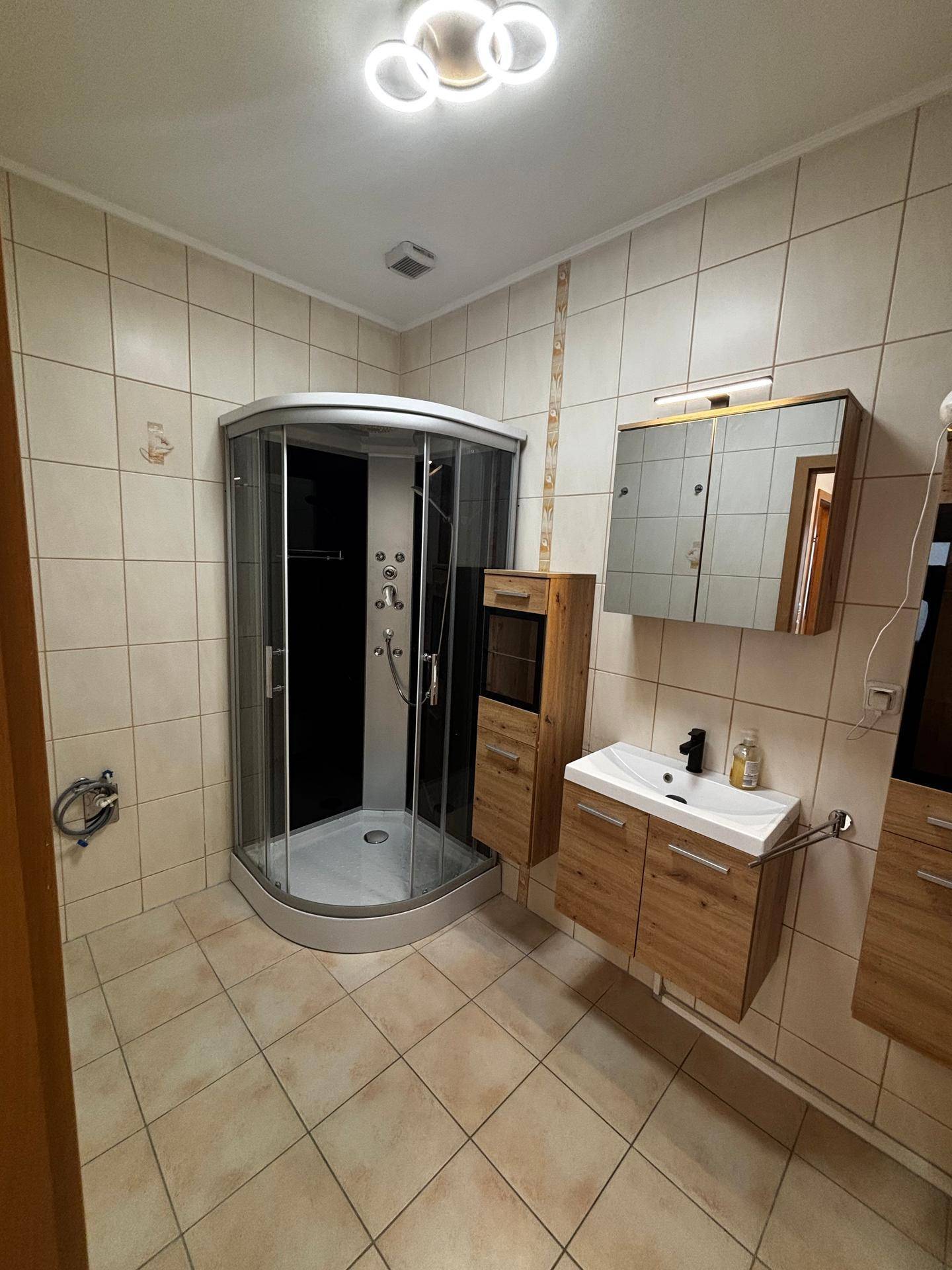 Badezimmer mit Eckdusche, modernem Waschtisch und Spiegelschrank, in gepflegtem Zustand.