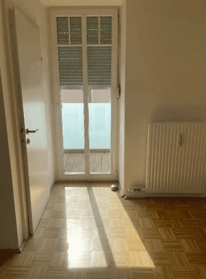 Heller Flur mit Parkettboden und Zugang zu einem Balkon, der viel Licht spendet.
