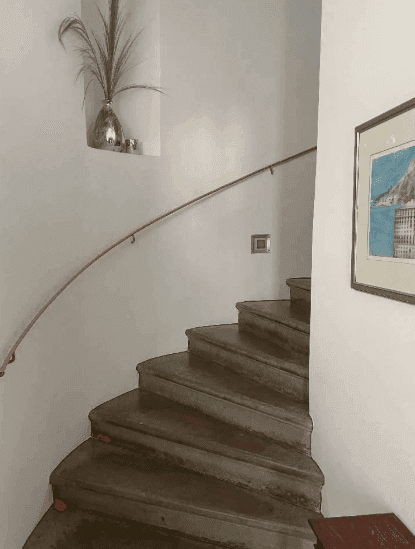 Geschwungene Holztreppe mit Handlauf, die verschiedene Etagen miteinander verbindet.