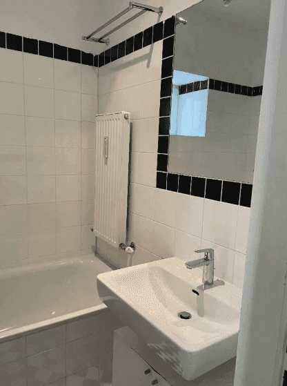 Modernes Badezimmer mit Waschbecken, Spiegel und Badewanne, in Schwarz-Weiß-Design.