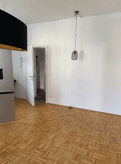 Leeres Zimmer mit Parkettboden und Deckenleuchte, bereit für neue Einrichtungsideen.